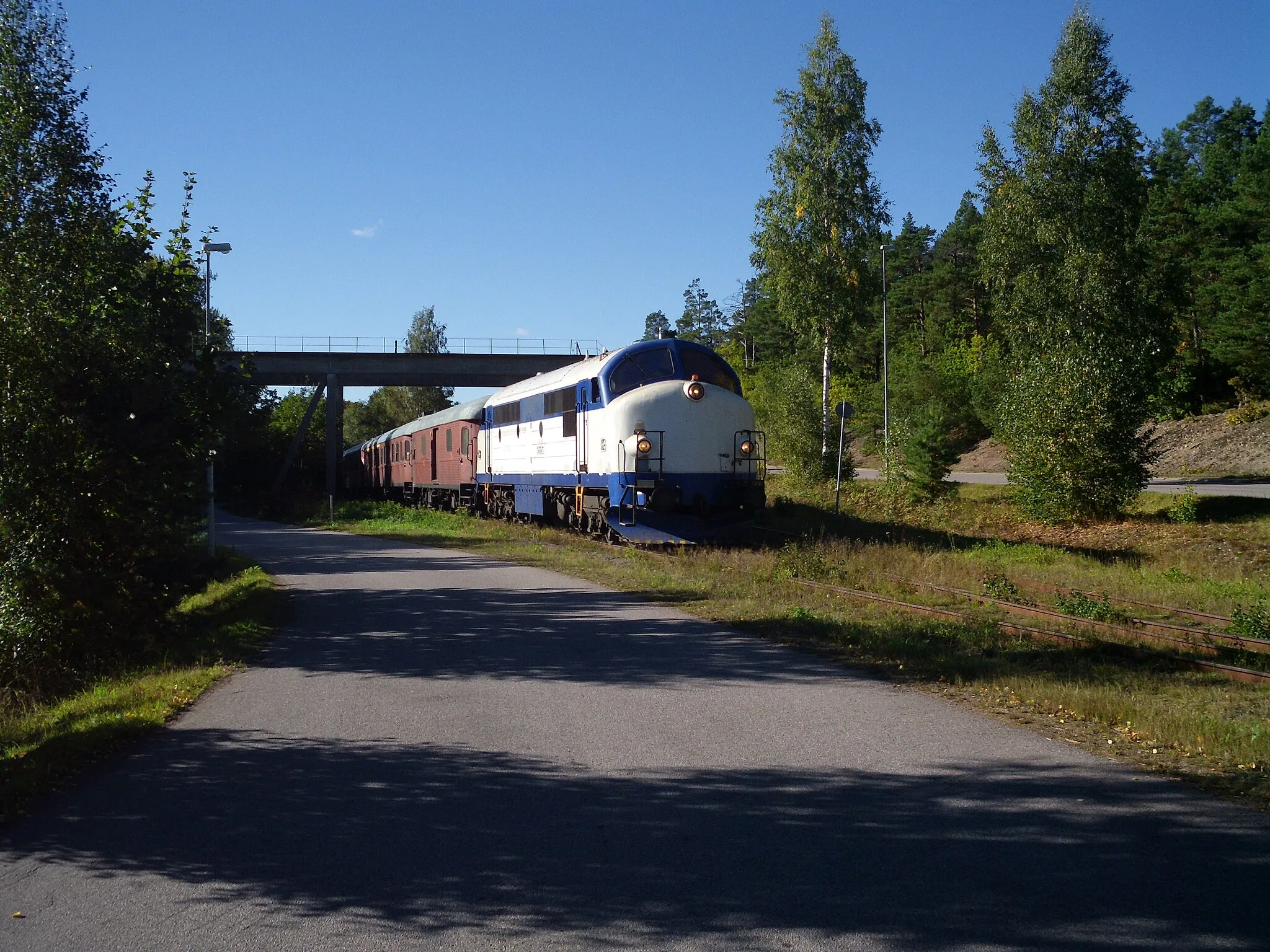 Photo showing: Tourist train passing under disused mining equipment, while returning from a business track towards Blomstermåla, Sweden.