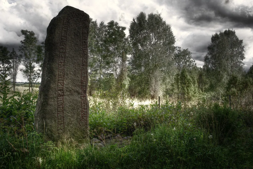 Photo showing: HDR-Aufnahme mit anschließendem TM aus einer 5er-Belichtungsserie des Runenstein Kårestad.
"Klackes söner läto hugga stenen efter sin fader och efter Kale och Viking, sina bröder."
"Klackes Söhne ließen diesen Stein ritzen für ihren Vater und für Kale und Viking, ihre Brüder."
Der Runenstein steht wahrscheinlich auf seinem ursprünglichen Platz und ist ein Gedenk- und kein Grabstein. Die Todesursache der 3 Männer ist unbekannt, ebenso der Name des Vaters. Das man den Namen Viking bekommen konnte zeigt, dass das Wort Wikinger eine positive Bedeutung hat. Dieser Name kommt auf über zwanzig Runensteinen vor.

Rundata Sm 11.