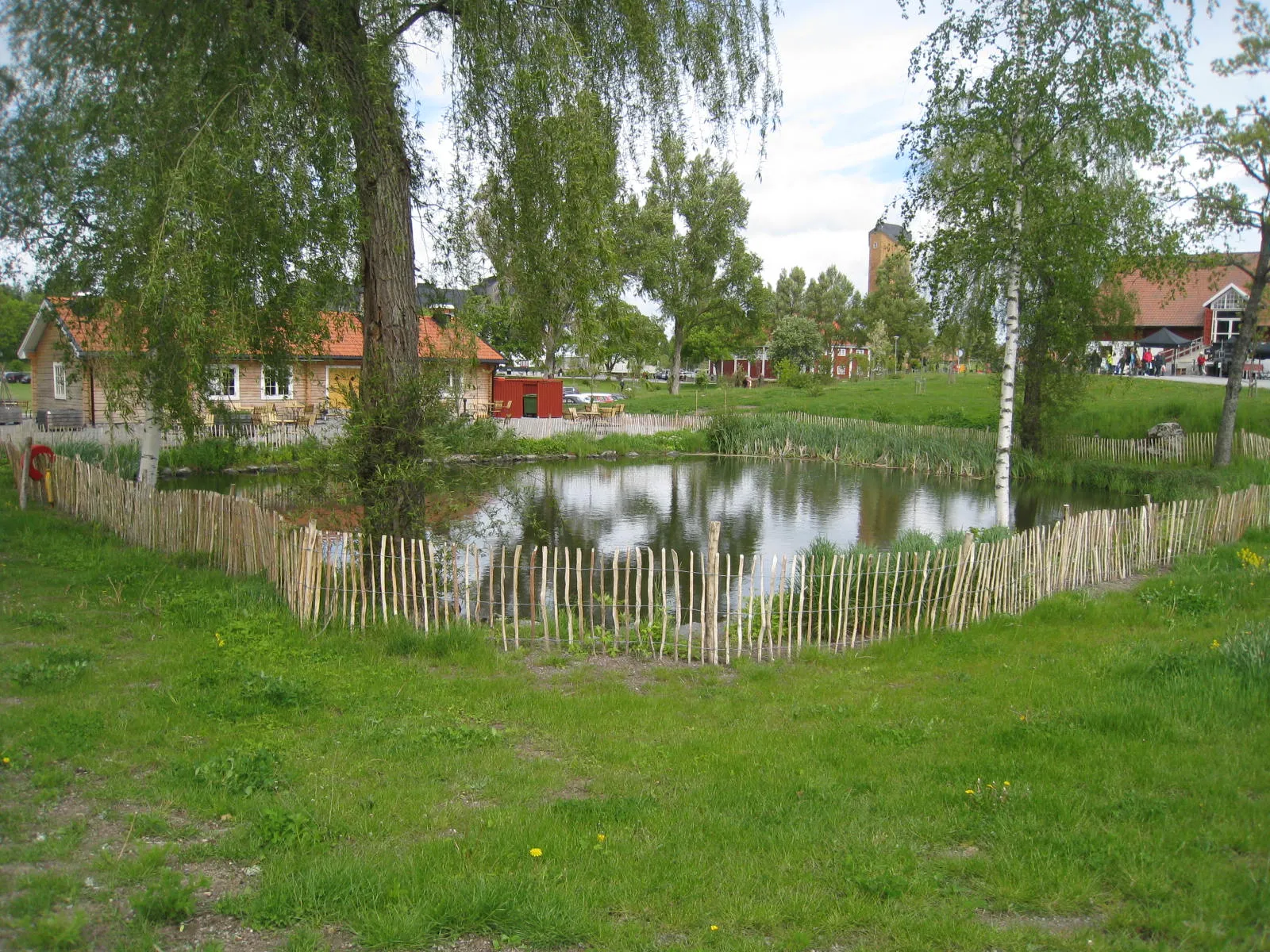 Photo showing: Wenngarn Slottsområde, Sigtuna, Uppland. Dammstugan och dammen. Stugan, som var från 1600-talet, brann ner i mars 2013. Dammstugan byggdes upp igen med gammal byggteknik.