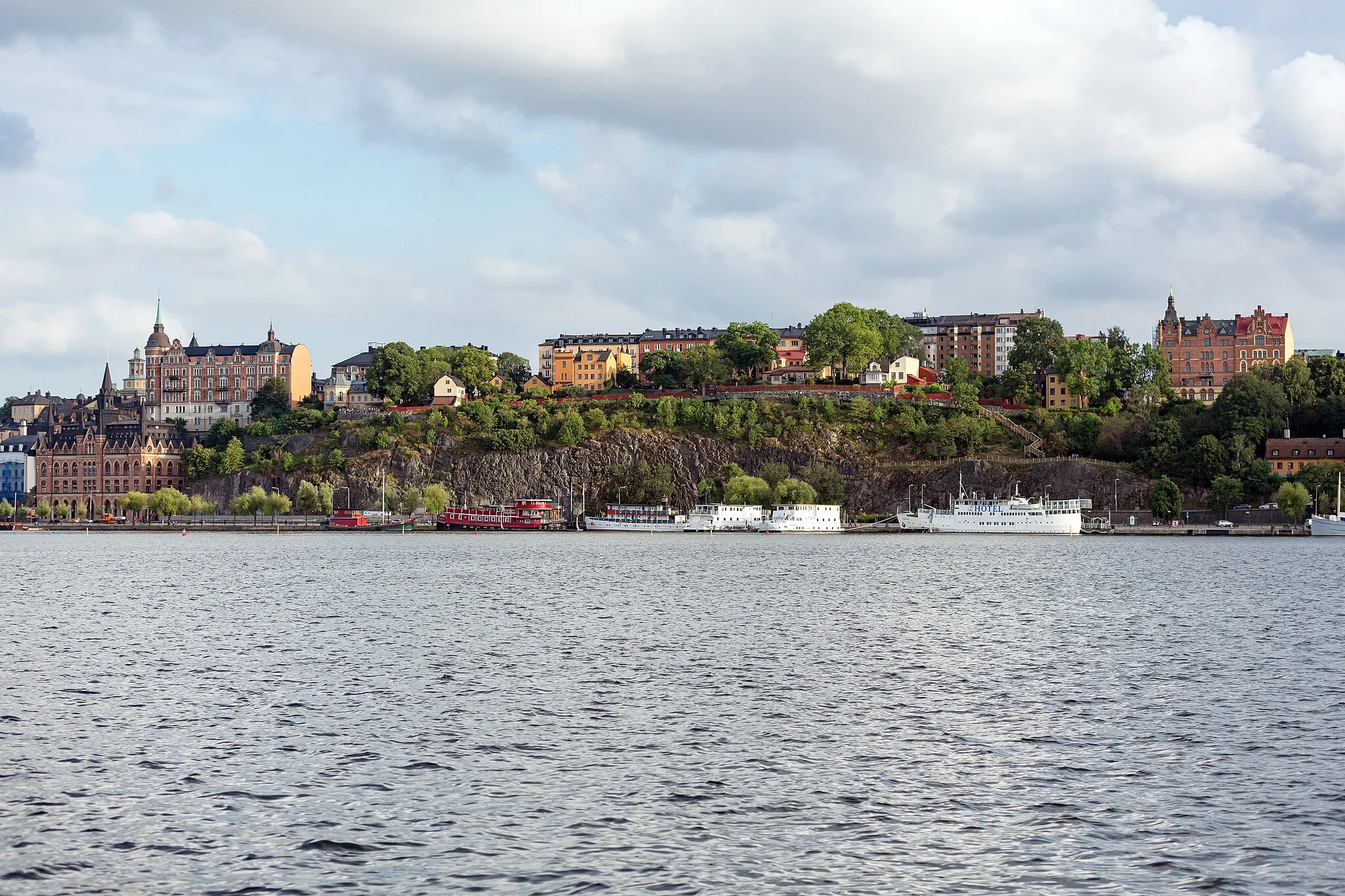 Photo showing: Mariaberget with Mariahissen, Ivar Los park, Mälarborgen and the hotel boats Den Röda Båten, Ran af Stokcholm and Rygerfjord at Riddarfjärden (Södermalm, Stockholm, Sweden), seen from Stadshusparken.