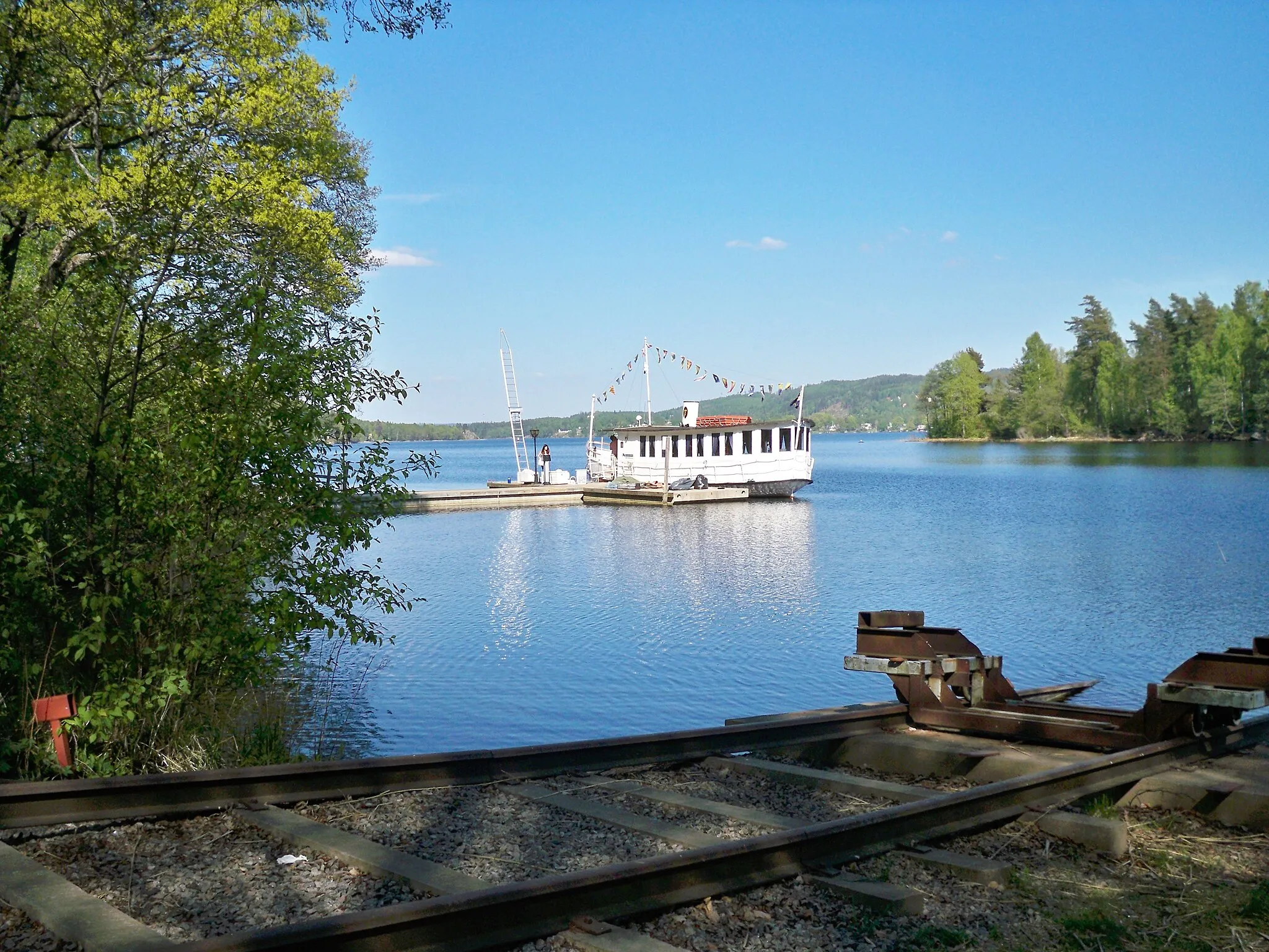 Photo showing: M/S Svanen (The Swan) moored to its quay in the southside Almenäs cove of the lake Öresjö. It has a restaurant on board and sometimes live musical entertainment during its sightseeing routes around the lake.