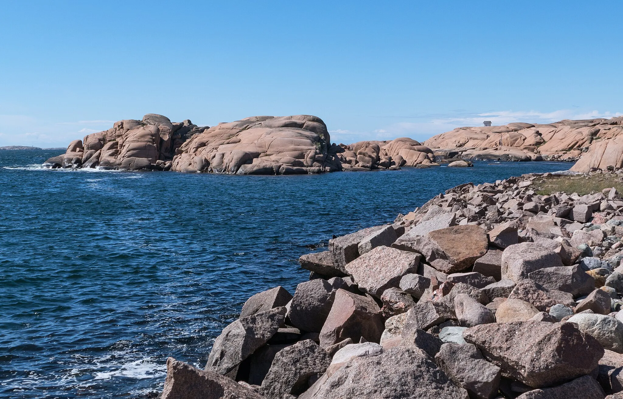 Photo showing: The glittering cliffs at Stångehuvud nature reserve in Lysekil, Sweden. The red granite cliffs are noted for their colour and the large feldspar and mica crystals (about 10 x 10 mm) that make any part of the cliffs glitter when the sun reflects off them. The cliffs in the nature reserve were saved from quarrying at the beginning of the 20th century by Calla Curman. She bought the whole area and donated it to Royal Swedish Academy of Sciences in 1925. This image illustrates how light, at different angles, is reflected off the feldspar crystals in the rock.