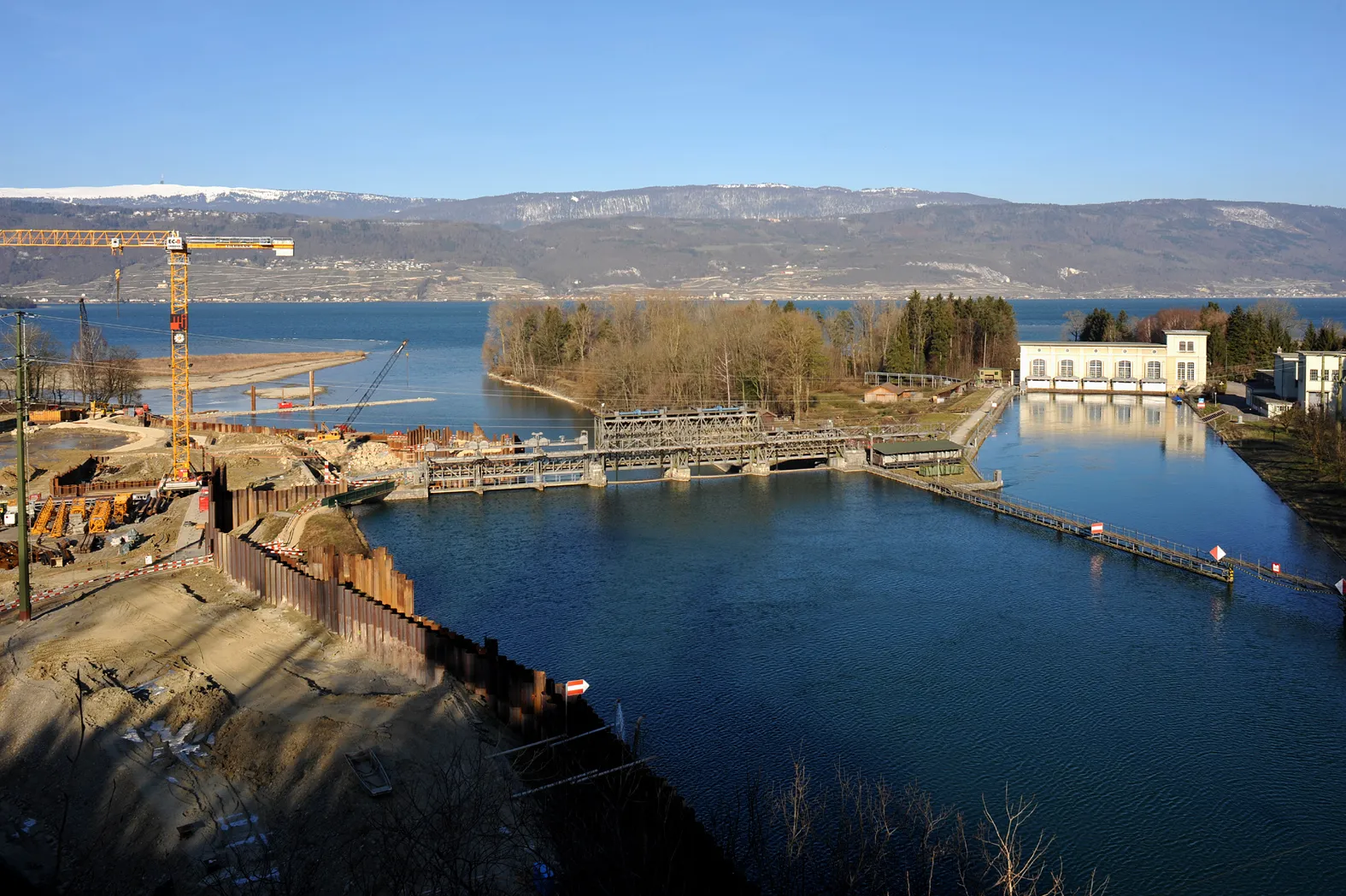 Photo showing: Hagneck canal of the Aar with the old dam and the hydroelectric powerstation; Berne, Switzerland.
Left below the dam, the dam be poured for the construction of the temporary pedestrian bridge. In the background Lake Biel left Ligerz and the Chasseral.