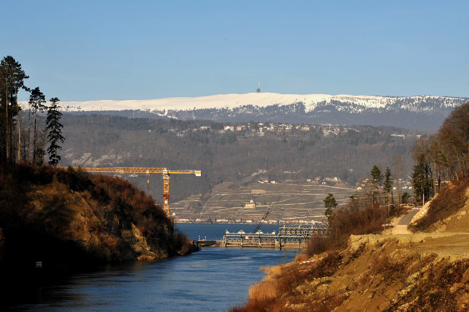 Photo showing: Hagneck canal of the Aar with the old dam; Berne, Switzerland.
Right the landslide (spring 2007), in the background Lake Biel the church of Ligerz the village Prêles and the Chasseral.