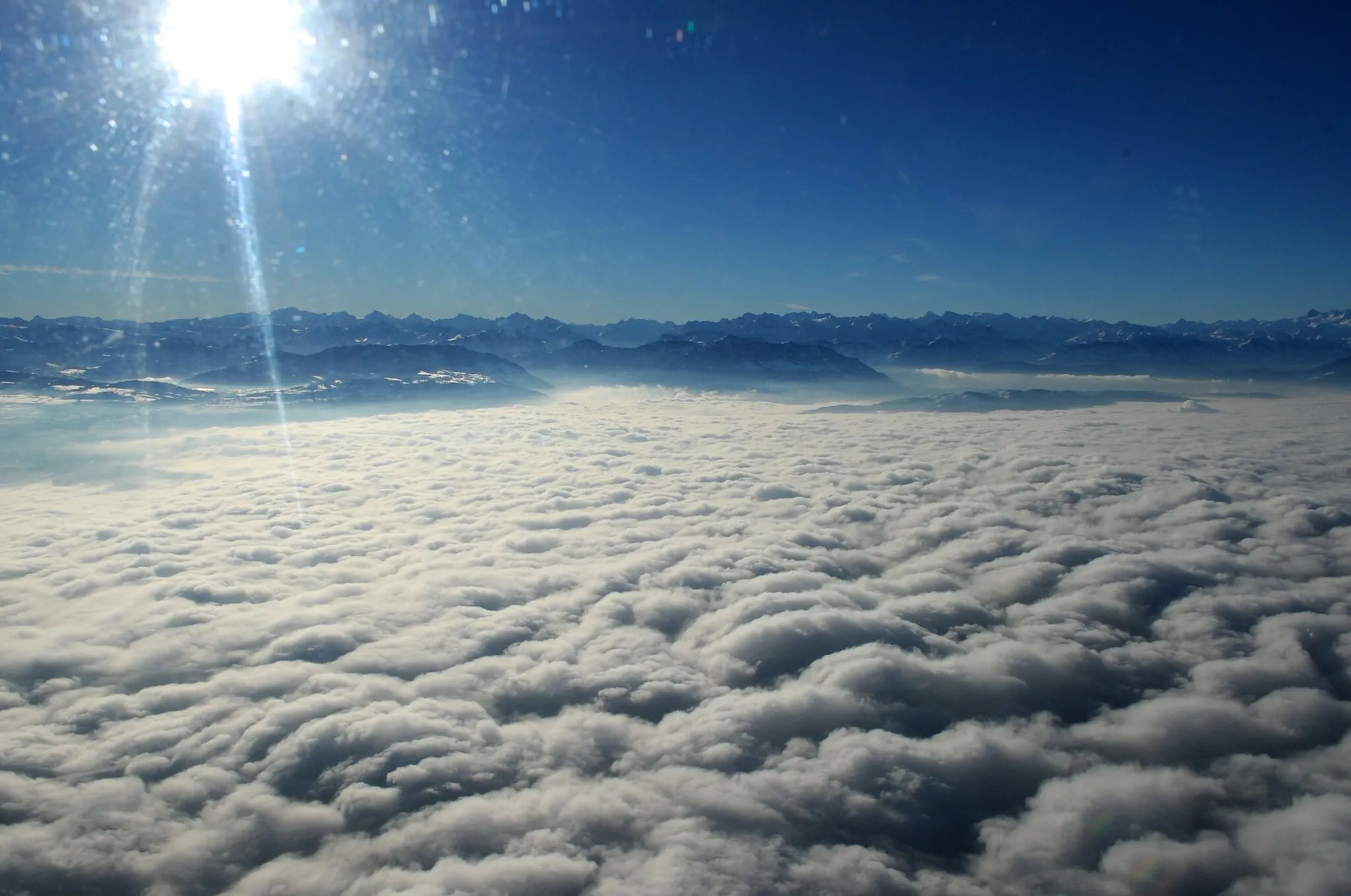 Photo showing: A blanket of clouds cover the terrain leading up to a section of Swiss Alps, as seen from the helicopter carrying U.S. Secretary of State John Kerry as he flew between Davos, Switzerland, and Zurich on Jan. 25, 2014. [State Dept. Photo/Public Domain]