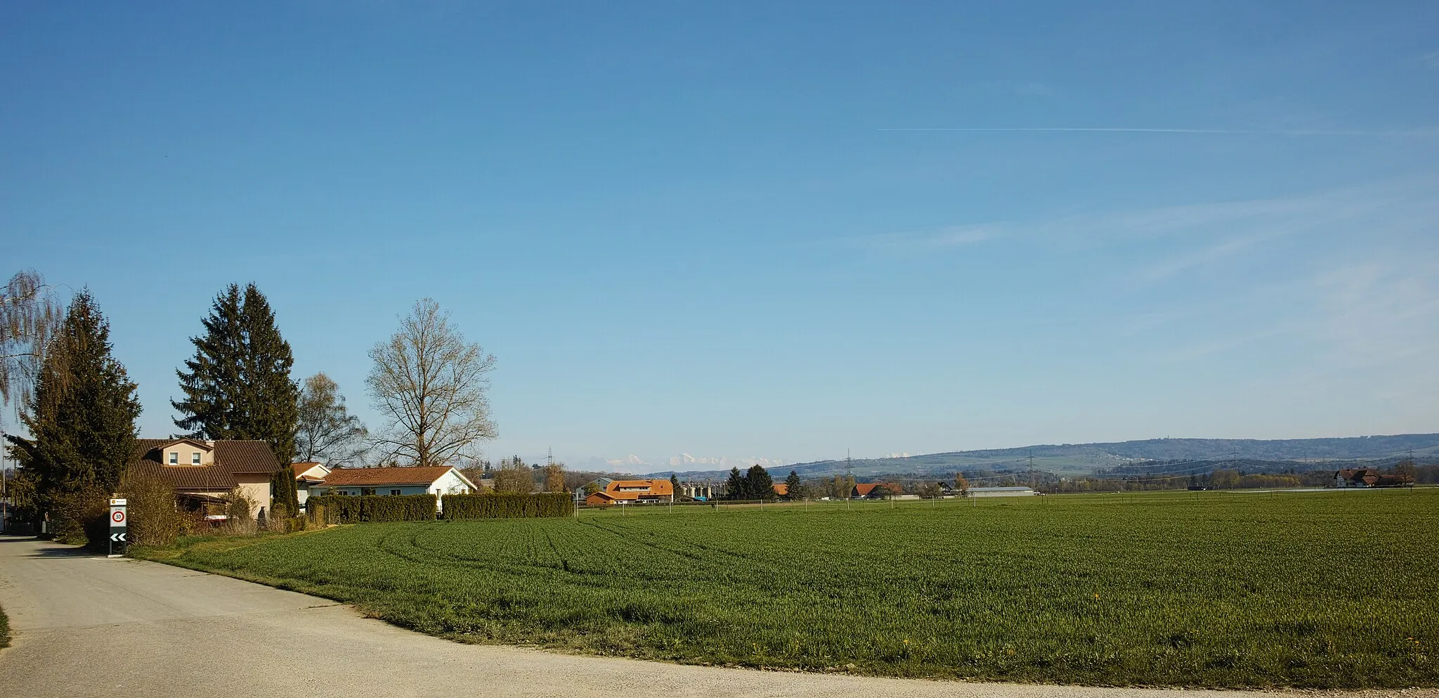 Photo showing: View of a field near Worben, canton of Bern, Switzerland, with some houses of Worben. In the background, the Bernese Alps are visible.