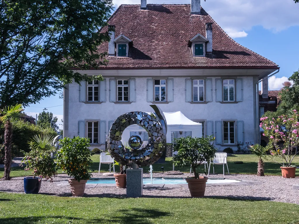 Photo showing: Seit 2013 ist der Metallplastiker Housi Knecht stolzer Besitzer des bescheidenen "Schlösschen" Rubigen, ein aus der Zeit der Berner Patrizier erhaltenes Herrenhaus im Dorf Rubigen Nähe Bern, Schweiz
Den dazugehörenden Park hat er umgebaut für eine Skulpturen-Ausstellung seiner eigenen Werke.