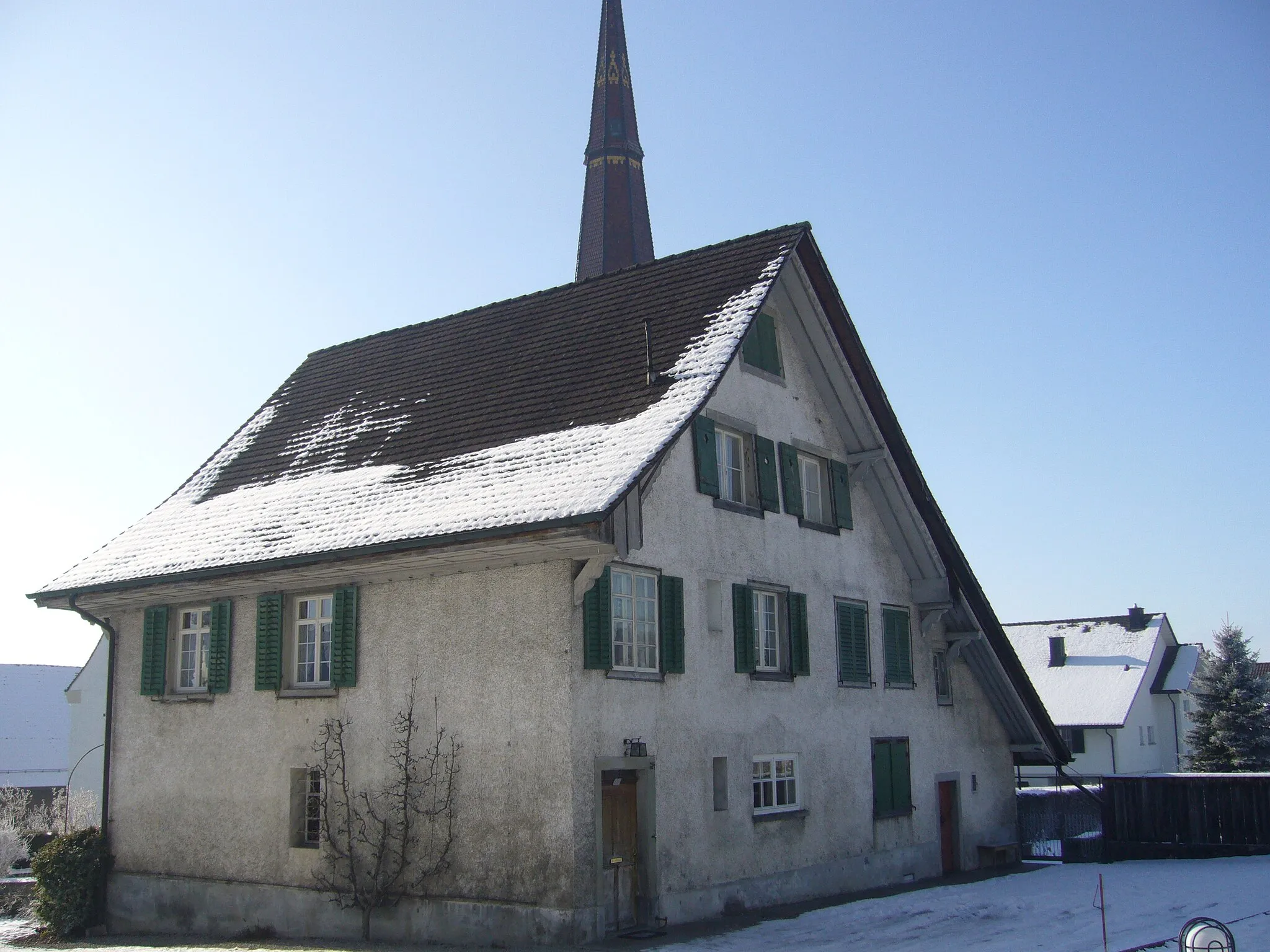 Photo showing: Wohnhaus (Altes Pfarrhaus) im Dorfkern von Stettfurt, mit dem Dache des Kirchturms im Hintergrunde.