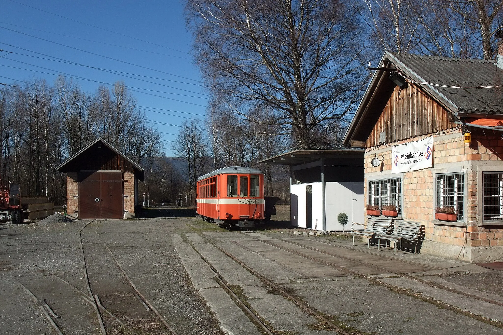 Photo showing: On 26 October 2011, the last trip was made with tourists by the association Rhein-Schauen over the railway bridge of the International Rhine Regulation (IRR) to this station at the quarry Kadelberg in Koblach. The red tram is one of three vehicles, which was acquired from the Swiss Trogen-railway in 2004 (today Appenzell Railways). The building on the left is the engine shed. Vorarlberg, Austria, Feb 23, 2014.

(14/17)