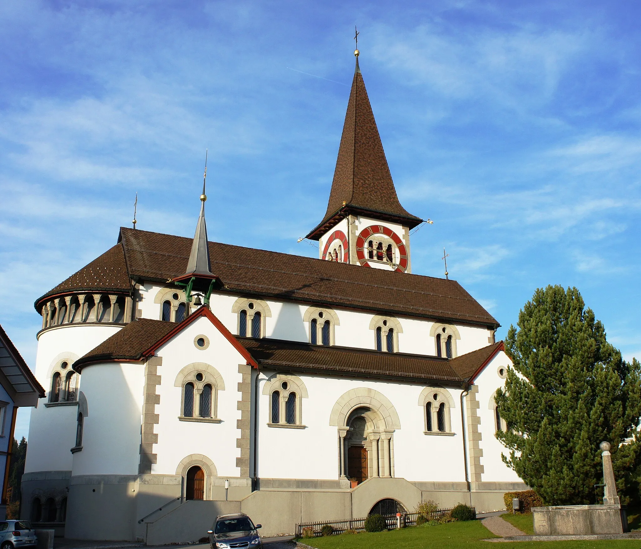 Photo showing: Blick aus Südwesten auf die Kirche in Haslen. Im Vordergrund der Dorfplatz mit kleinem Park und Brunnen.