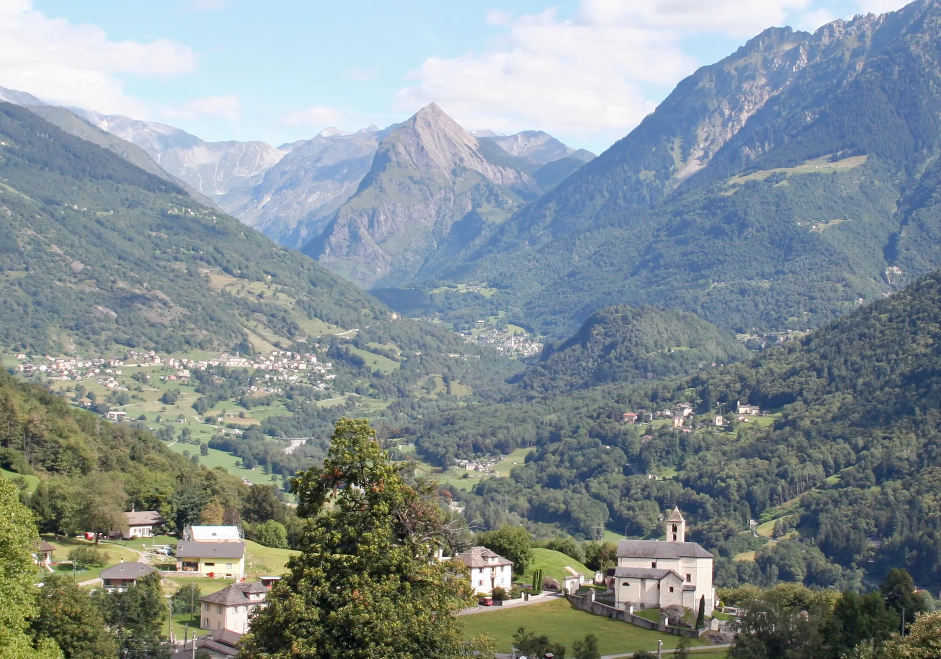 Photo showing: de:Vale di Blenio nach Norden, vorne die Kirche von Corzoneso, de:Sosto (2221 m) in der Bildmitte.