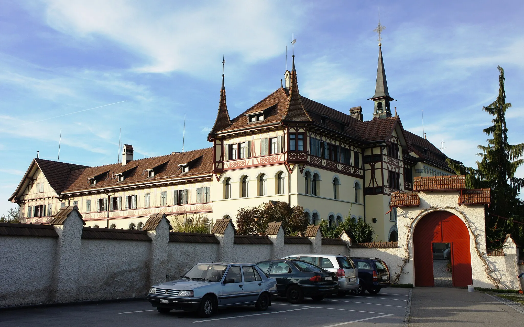 Photo showing: Das Kloster Scholastika in Tübach vom Parkplatz aus (von Südosten). Rechts das Eingangs-Tor zum Vorplatz (Zugang zur Kirche und Pforte). Links hinter der Mauer ist der Klostergarten (Klausur-Bereich). In der Mitte der Haupttrakt und rechts davon die Klosterkirche.