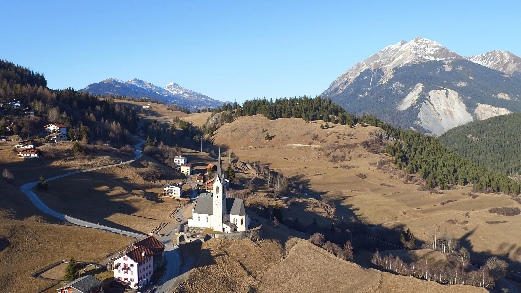 Photo showing: Aerial recording of Church S. Gieri, in the background Motta Vallac (Salouf, Grisons, Switzerland)