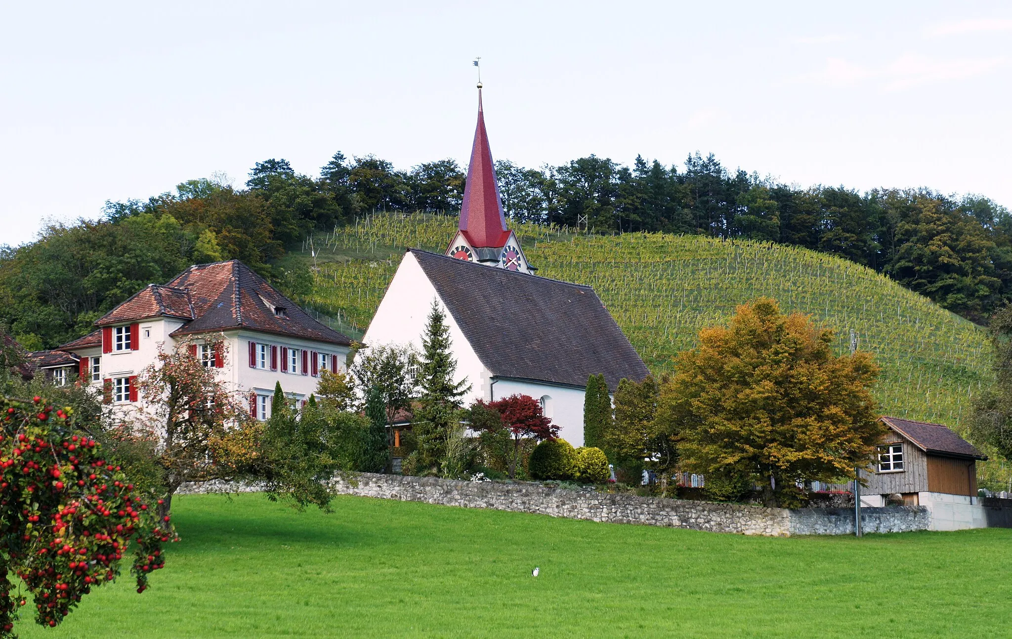 Photo showing: Die ref. Kirche Eichberg aus Süden. Links davon steht das Pfarrhaus, rechts der ummauerte Friedhof. Im Hintergrund der Rebberg vom Hochchapf.