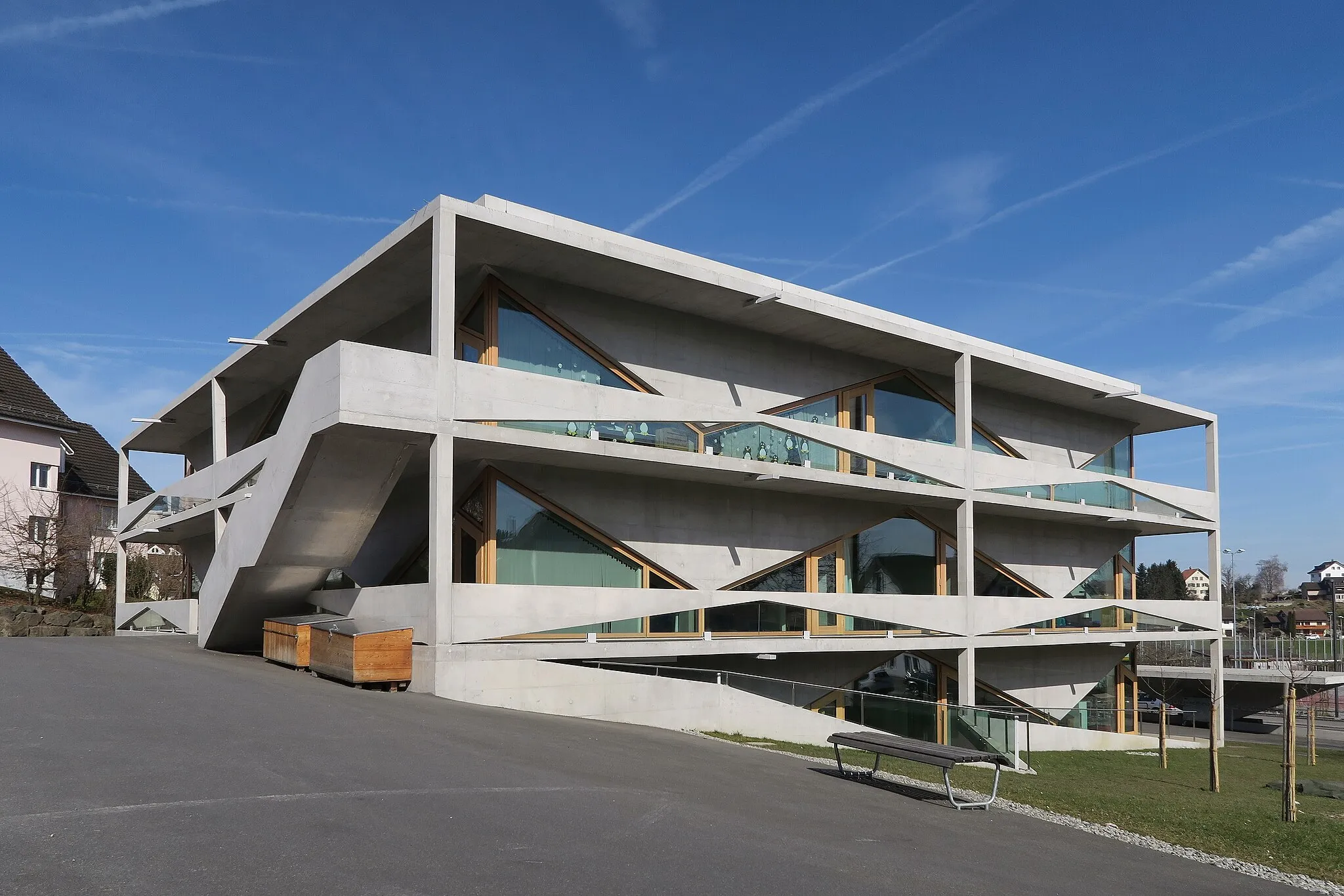 Photo showing: The architecture of the new schoolhouse impresses with lightness of a structure in exposed concrete. Even if it's not everybody's taste, anyhow it's not humdrum. It was completed in 2013. Despite the unusual construction, it has cost less than was budgeted.