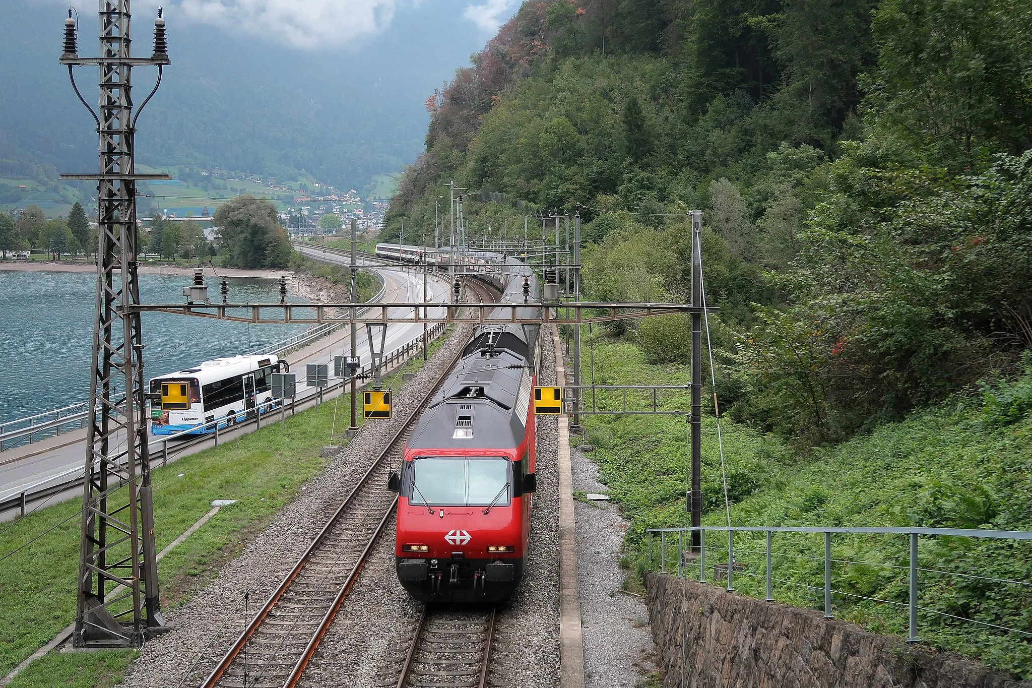 Photo showing: Above the portal on the eastern side of the Bommerstein tunnel II towards Walenstadt. The former track from 1859 to the old tunnel ran directly along the lake. The smileys mark a protection section on the catenary. Here two different feed-ins come together. The main switch on the locomotive must be turned off for a moment. Switzerland, Sep 3, 2018. (3/27)