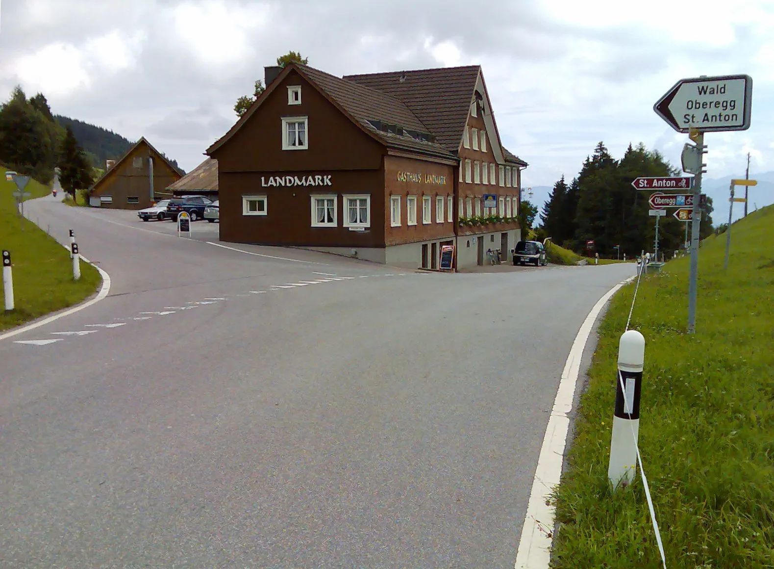 Photo showing: Strassenverzweigung auf dem Ruppen (Pass), Blickrichtung Ost, im Rücken die Strasse nach Trogen, geradeaus Strasse nach Altstätten (rechts in der Wiese steht der Wegweiser; Wald Oberegg St. Anton (schwarz auf weissem Grund) darunter erkennt man noch den Wegweiser für die Radroute (rot) und den Wanderweg (gelb)