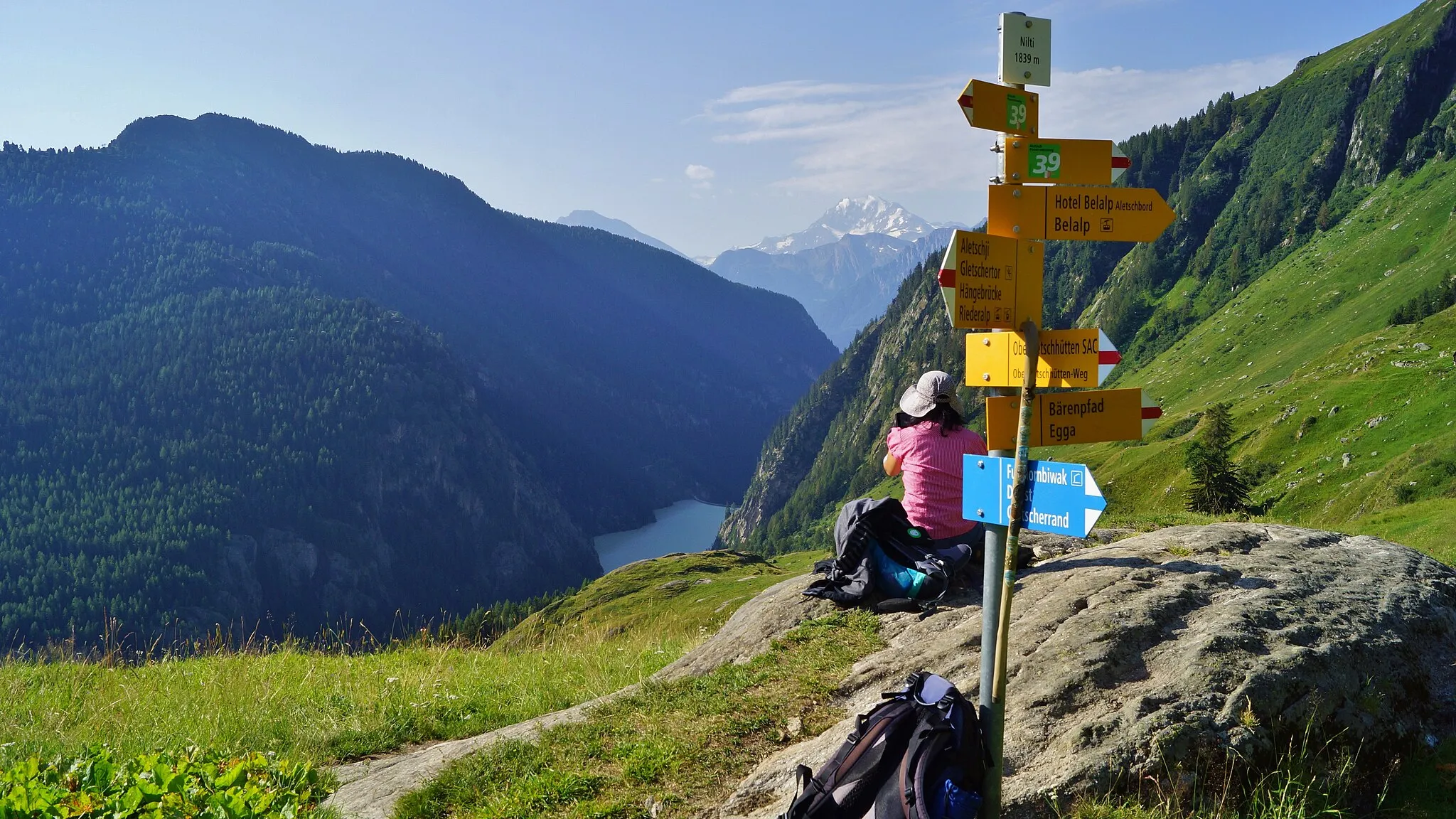 Photo showing: Wegweiser am Aletsch-Panoramaweg [39] in Nill (angeschrieben: Nilti) mit Blick zum Stausee Gibidum.