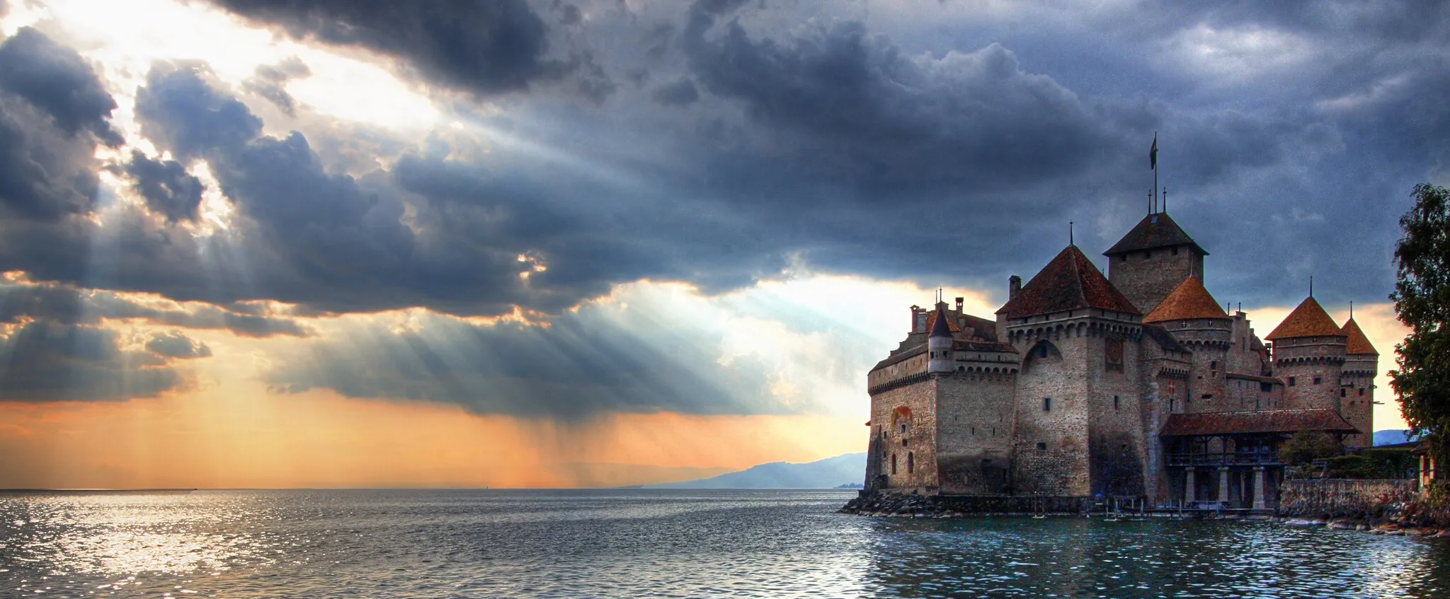 Photo showing: The sun sets on Château de Chillon while a storm brews over Lausanne.