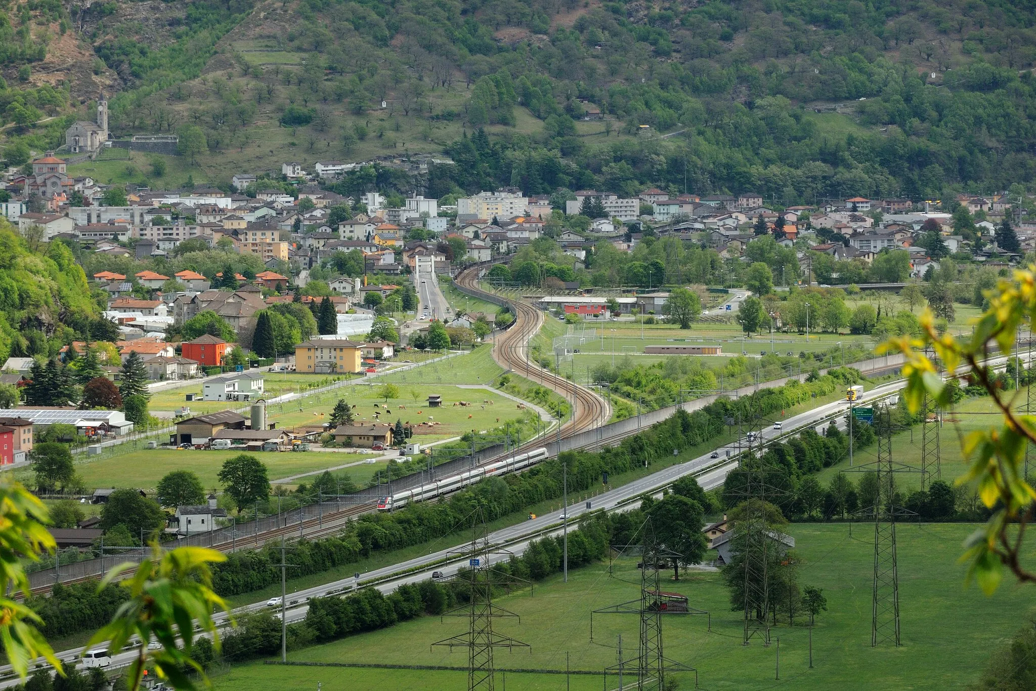 Photo showing: 19 April 2017 weather south of Pollegio at Biasca, looking South-East to the town and Chiesa San Pietro e Paolo (southern approach to the Gotthard Base Tunnel). Partly sunny, maximum temperature: ~12°C. This image is part of a series showing the influence of the Alps on European climate.