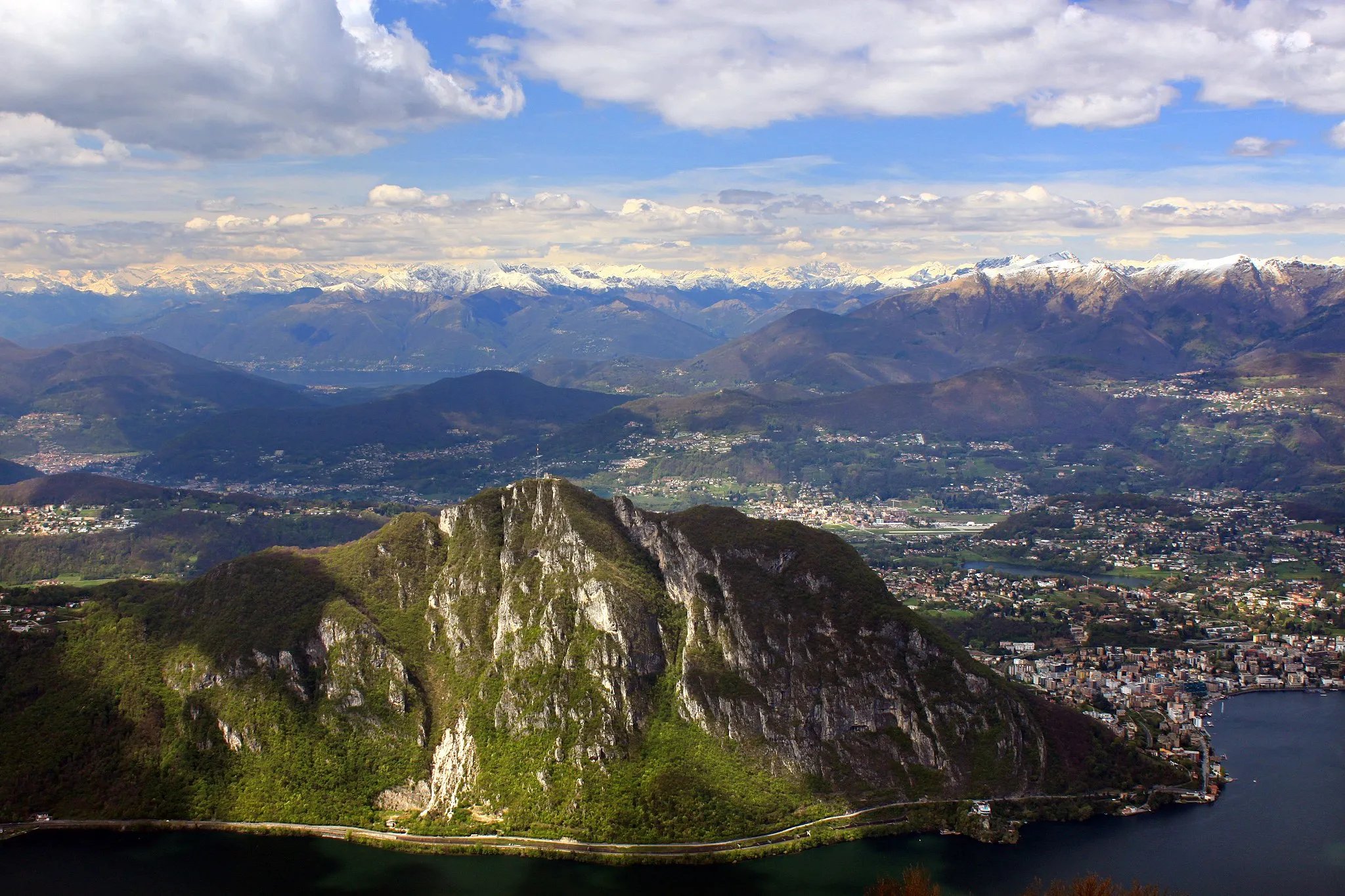 Photo showing: Panorama vom Sighignola auf den Luganersee mit dem Monte San Salvatore ( 912 m.ü.M.) in der Schweiz und Lugano. Am Hang des Monte Salvatore erstreckt sich die national bedeutende Trockenwiese gleichen Namens. Der Gipfel des Monte Sighignola ( 1302 m.ü.M.) liegt direkt auf der Grenze zwischen der Schweiz und Italien.