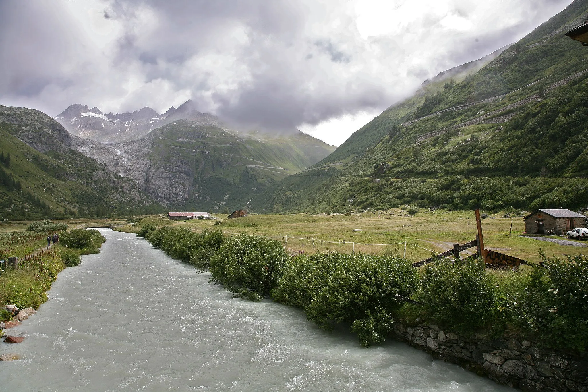 Photo showing: Upper reaches of the Rhone river, Rhone glacier and Furka mountain pass in the background.