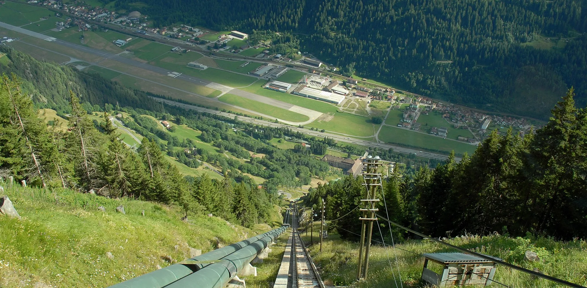 Photo showing: View down the Ritom funicular in the Swiss canton of Ticino. Ambri Airport can be seen at the bottom of the valley. For more information, see the Wikipedia articles Ritom funicular and Ambri Airport.