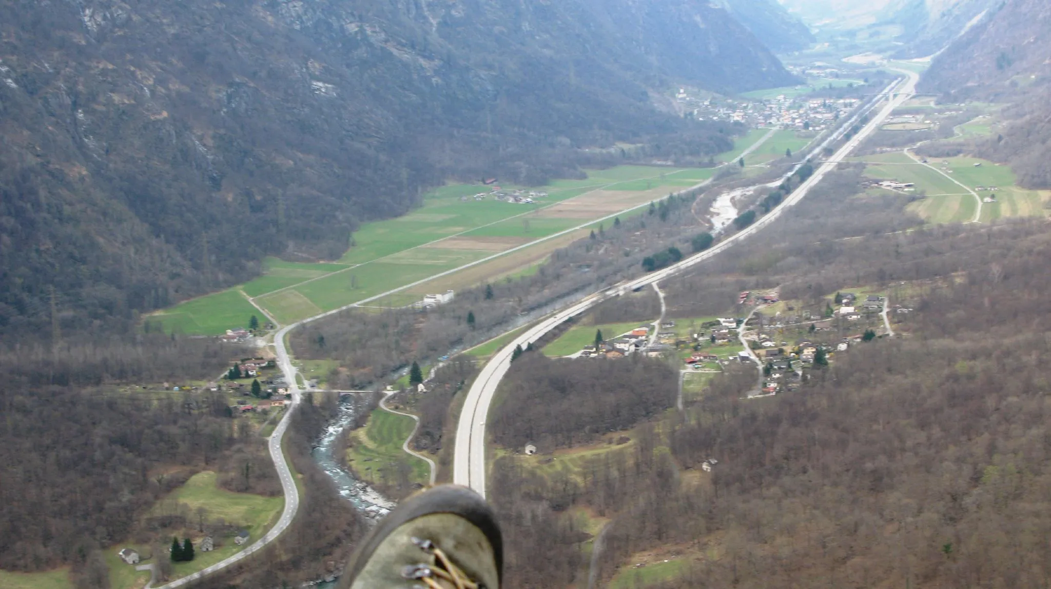 Photo showing: View from a paraglider over the plain between Sorte (in the foreground on the right of the motorway) and Lostallo (in the background on the left of the motorway) in the Swiss canton of Grisons. In the centre of the picture, between the highway and the main road 13, is the nationally important alluvial zone Rosera, through which the Moësa flows. In the background, the nationally important dry grassland/pasture Von (area of over 8 ha) is visible on the right of the motorway at the height of Lostallo.
