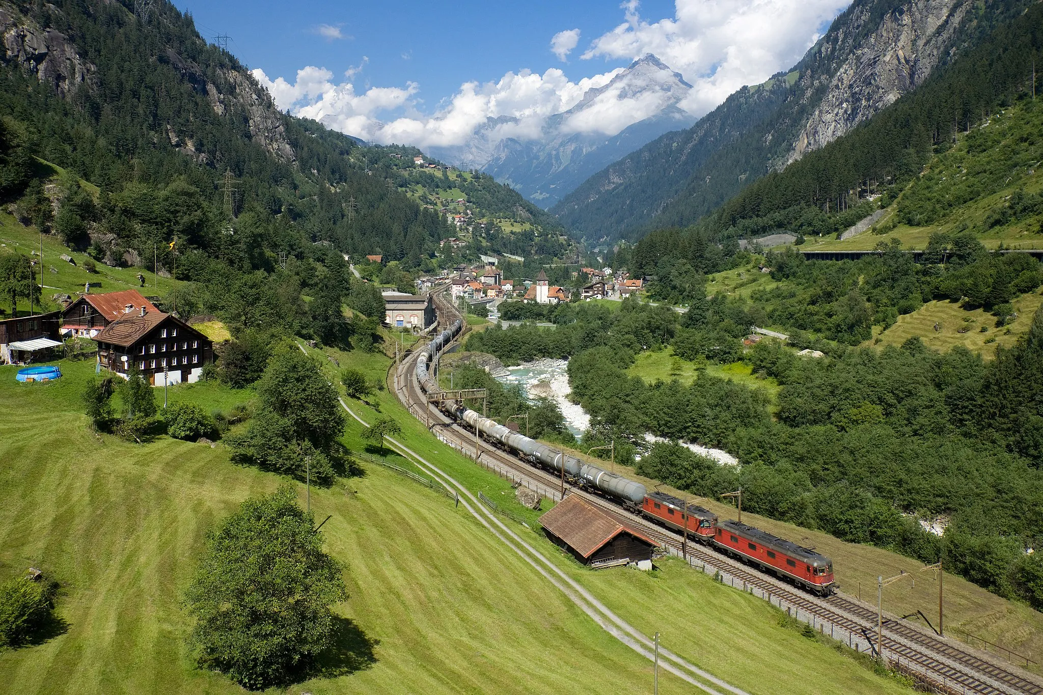 Photo showing: A SBB-CFF-FFS Re 6/6 and Re 4/4 II at the front plus another Re 4/4 II pushing at the rear (barely visible) haul a 1500 ton oil train uphill on the Gotthard line. Picture taken near Gurtnellen, Switzerland.
