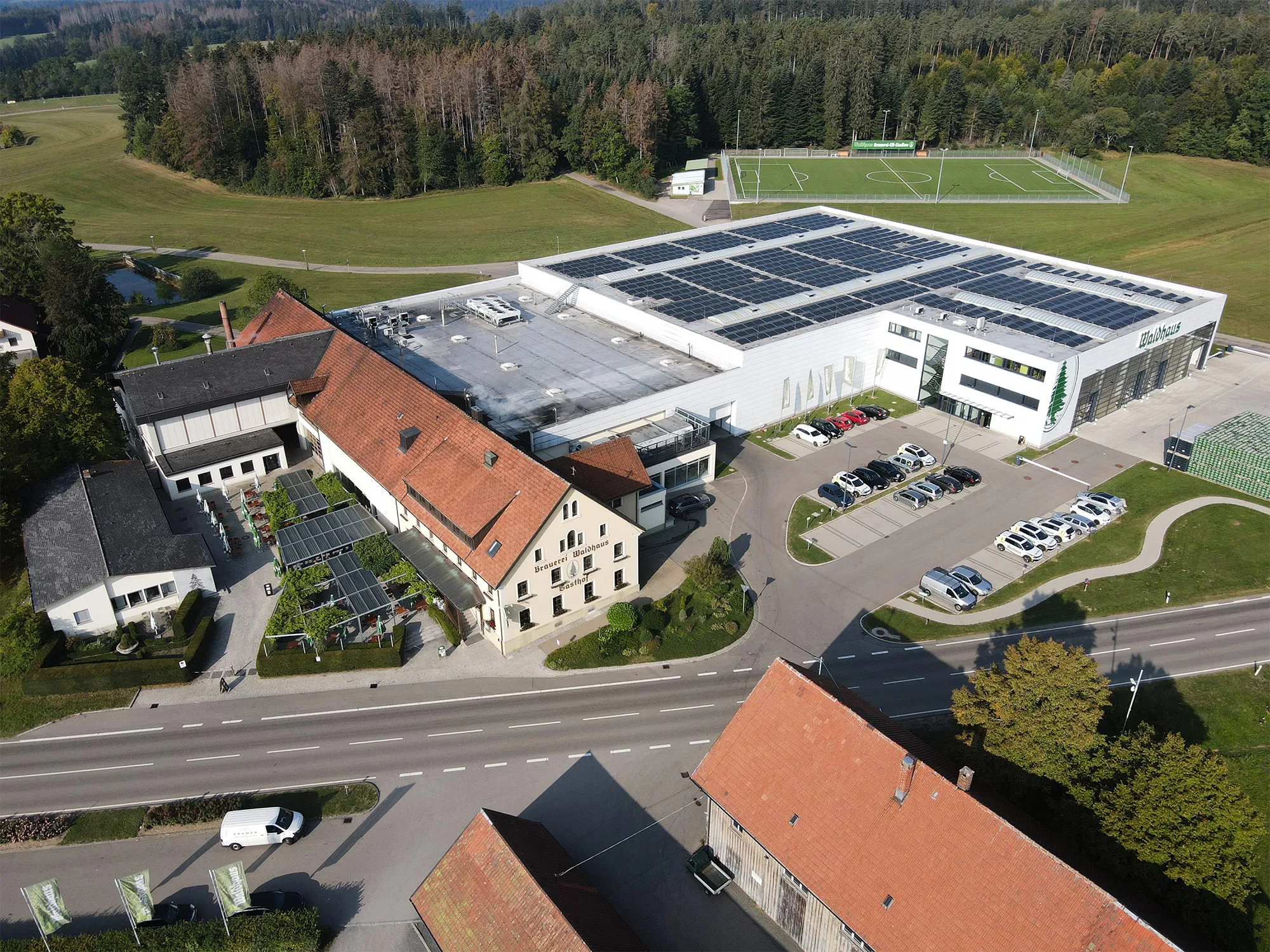 Photo showing: Eine Drohnenaufnahme der Privatbrauerei Waldhaus. Zu sehen sind Spielfeld des SV Waldhaus, die weiße Logistikhalle, der Brauereigasthof im Vordergrund und der Biergarten der Privatbrauerei.