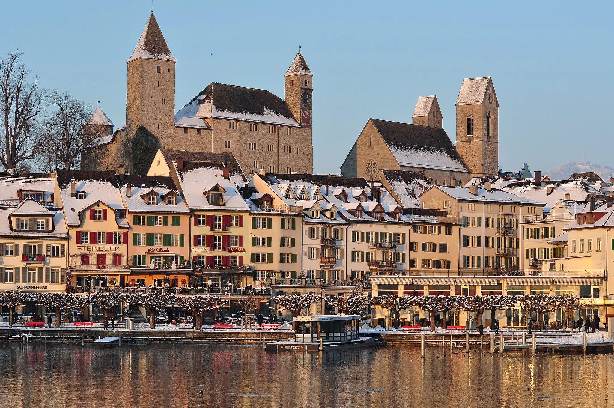 Photo showing: Rapperswil Altstadt, as seen from Seedamm, Fischmarktplatz to the right, Lindenhof, Rapperswil castle and Stadtpfarrkirche (St. John's Church) respectively Bachtel mountain (to the right) in the background.