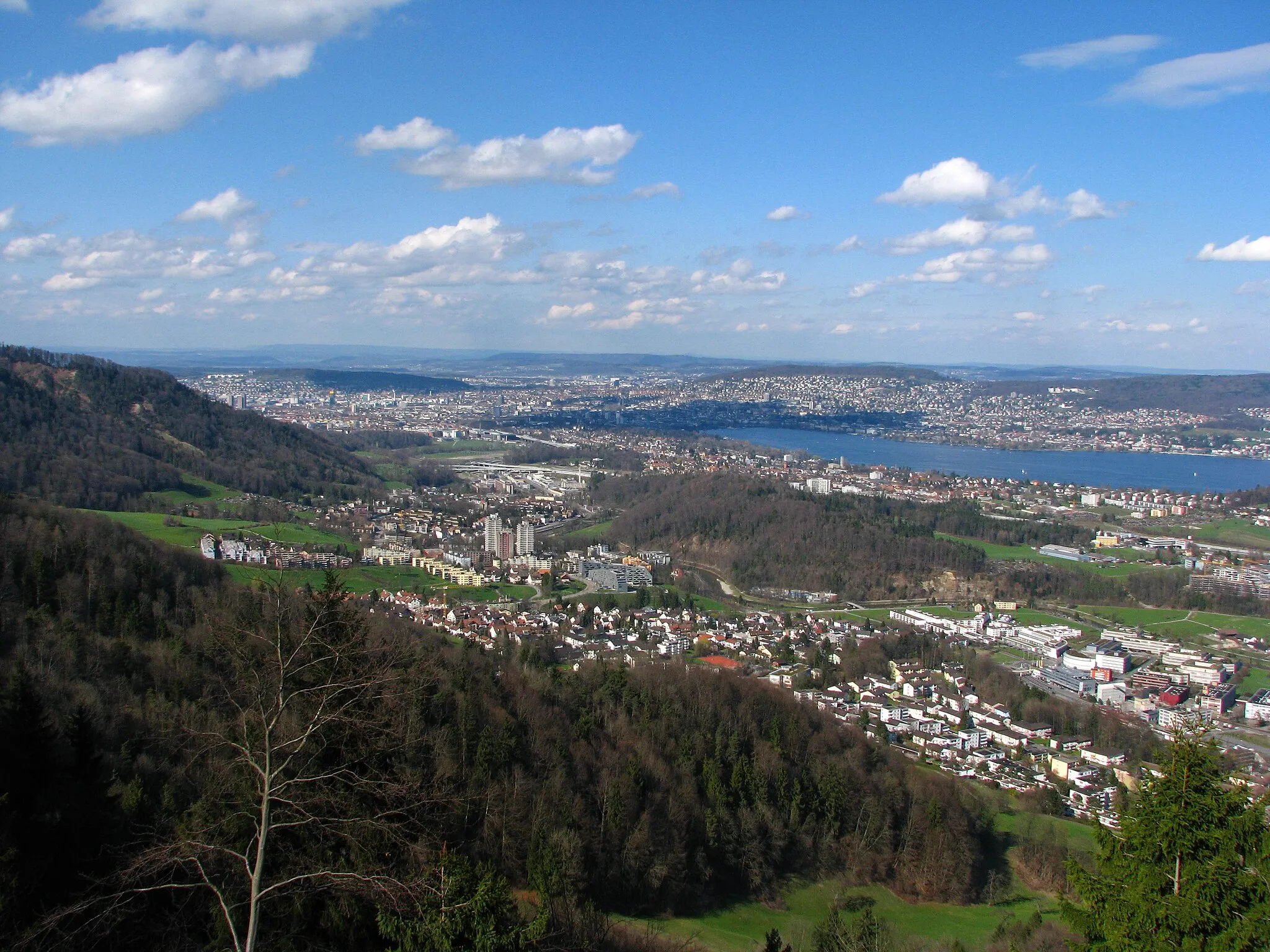 Photo showing: Zürich-Leimbach, lower Sihl valley, inner city and Käferberg (to the left) in the background, as seen from Felsenegg heading to Zürich-Nord.