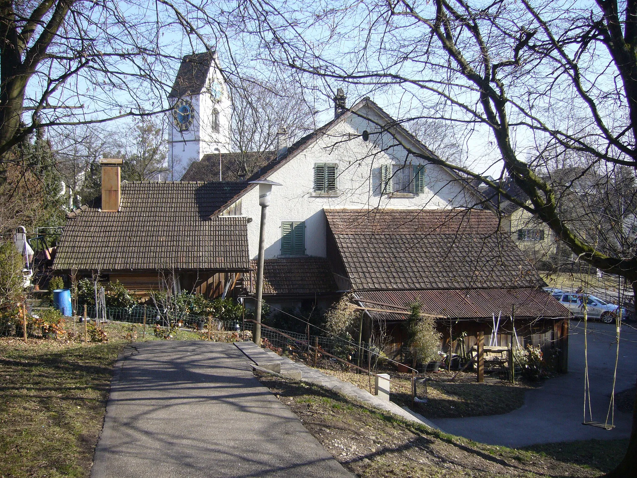 Photo showing: Blick vom Alpenrösliweg auf Hinterſeite eines Wohn- und Geſchäfftshauſes mit angebauten Schöpfen an der Gerlisbergſtraß zů Baſſersdorf (abgebrochen im Februar 2016); im Hindergrunde links der Bildmitte Turm der reformirten Kirch.