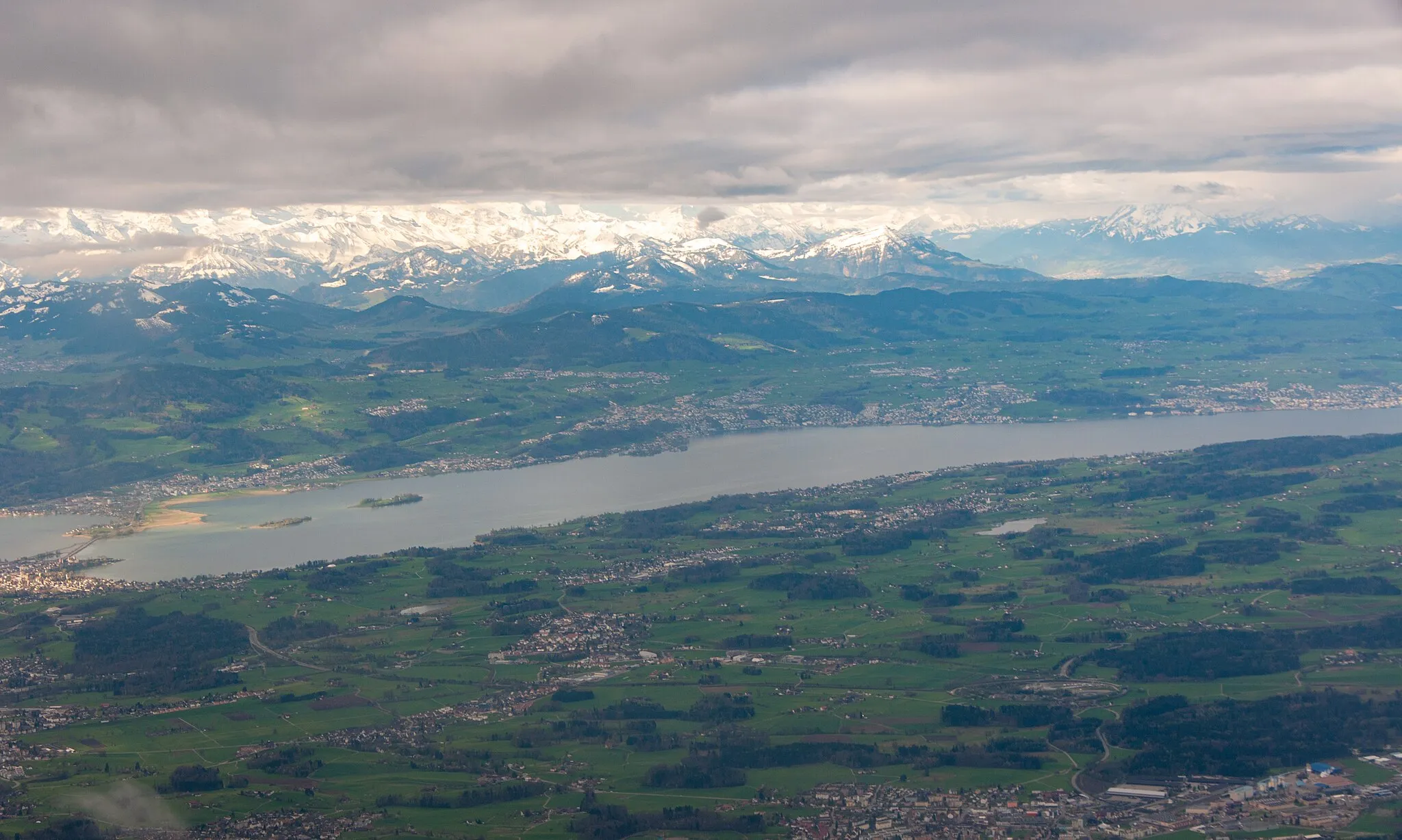 Photo showing: Aerial view of Lake Zurich with the dam of Rapperswil and the alps.