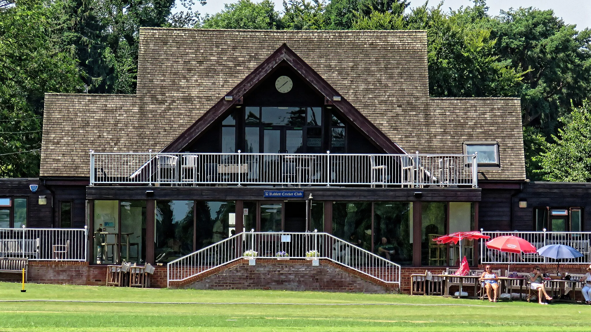 Photo showing: Radlett Cricket Club pavilion during a  July 2019 Tuesday public 45-over Minor Counties cricket match between Hertfordshire County Cricket Club and Berkshire County Cricket Club, at the Radlett Cricket Club ground in Hertfordshire, England. The game was part of the elimination stage for the 2019 National 60+ / 70+ County Cricket Championship between Hertfordshire 50+ - 60+ 1st XI[1] and Berkshire Cricket Board 60+ 1st XI. Mobile device view: Wikimedia (as at July 2019) makes it difficult to immediately view photo groups related to this image. To see its most relevant allied photos, click on Radlett Cricket Club, and this uploader's Cricket photos. You can add a beta click-through 'categories' button to the very bottom of photo-pages you view by going to settings... three-bar icon top left. Desktop view: Wikimedia (as at July 2019) makes it difficult to immediately view the helpful category links where you can find images related to this one in a variety of ways; for these go to the very bottom of the page. This image is one of a series of date and/or subject allied consecutive photographs kept in progression or location by file name number and/or time marking. Camera: Canon PowerShot SX60 HS Software: File lens-corrected, optimized, perhaps cropped, with DxO PhotoLab 2 Elite, and likely further optimized with Adobe Photoshop CS2.