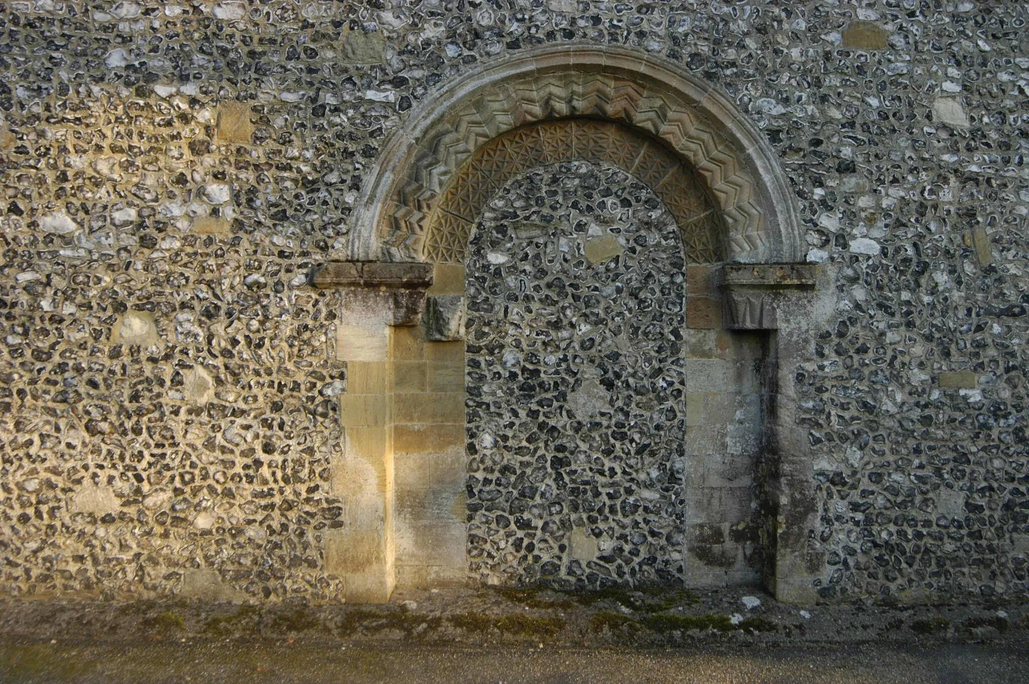 Photo showing: ), of filled in Norman northern doorway of St. Mary's church, Kingsclere, Hampshire. Flint added in C19th.