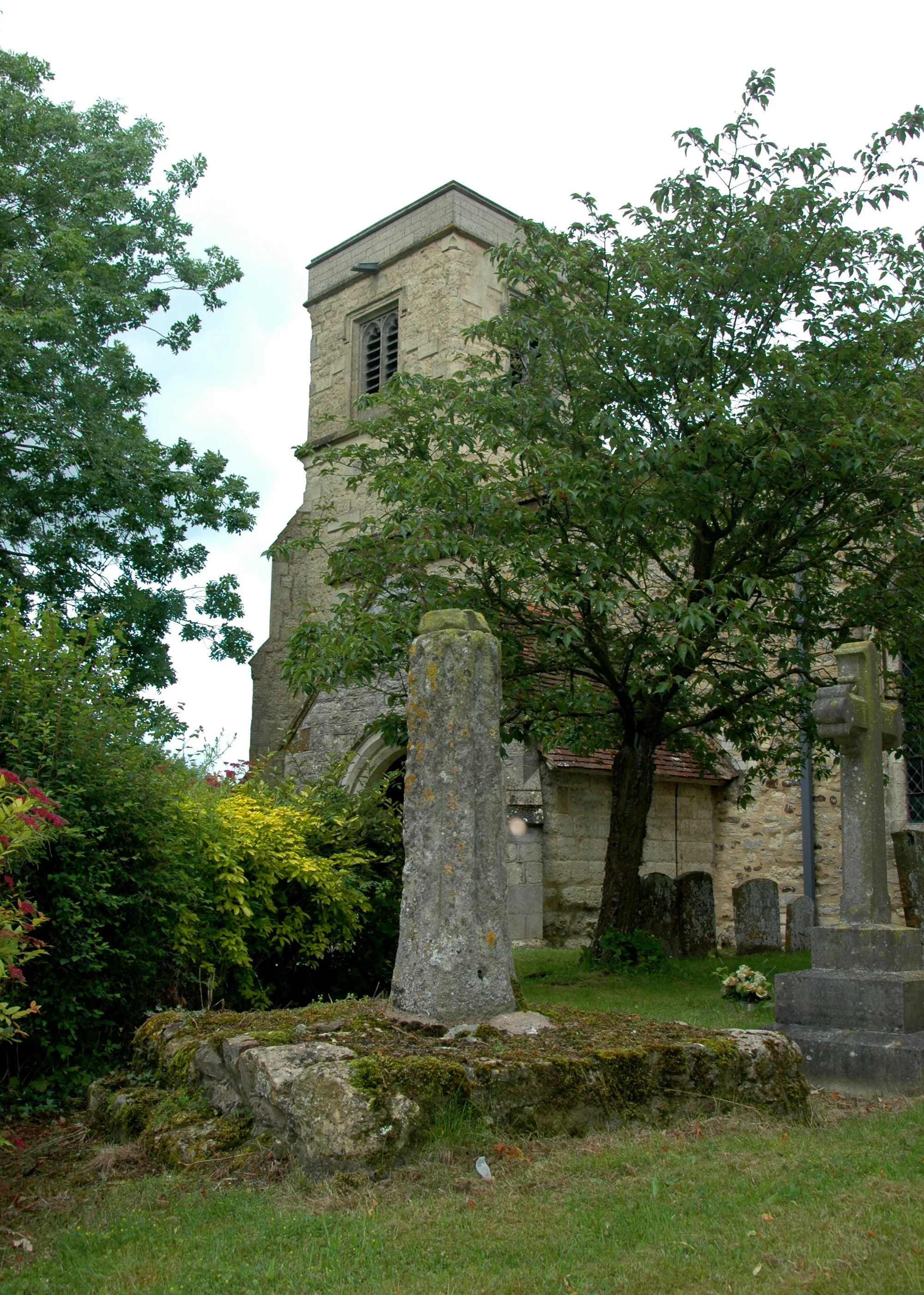 Photo showing: Holy Trinity parish church, Drayton Parslow, Buckinghamshire: base and broken shaft of churchyard cross, with the 15th-century west tower of the church in the background