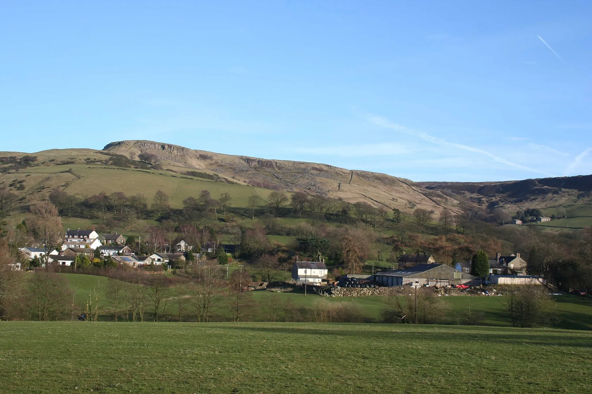 Photo showing: The village of Combs, Derbyshire, with Castle Naze hillfort and the plateau of Combs Moss in the background.