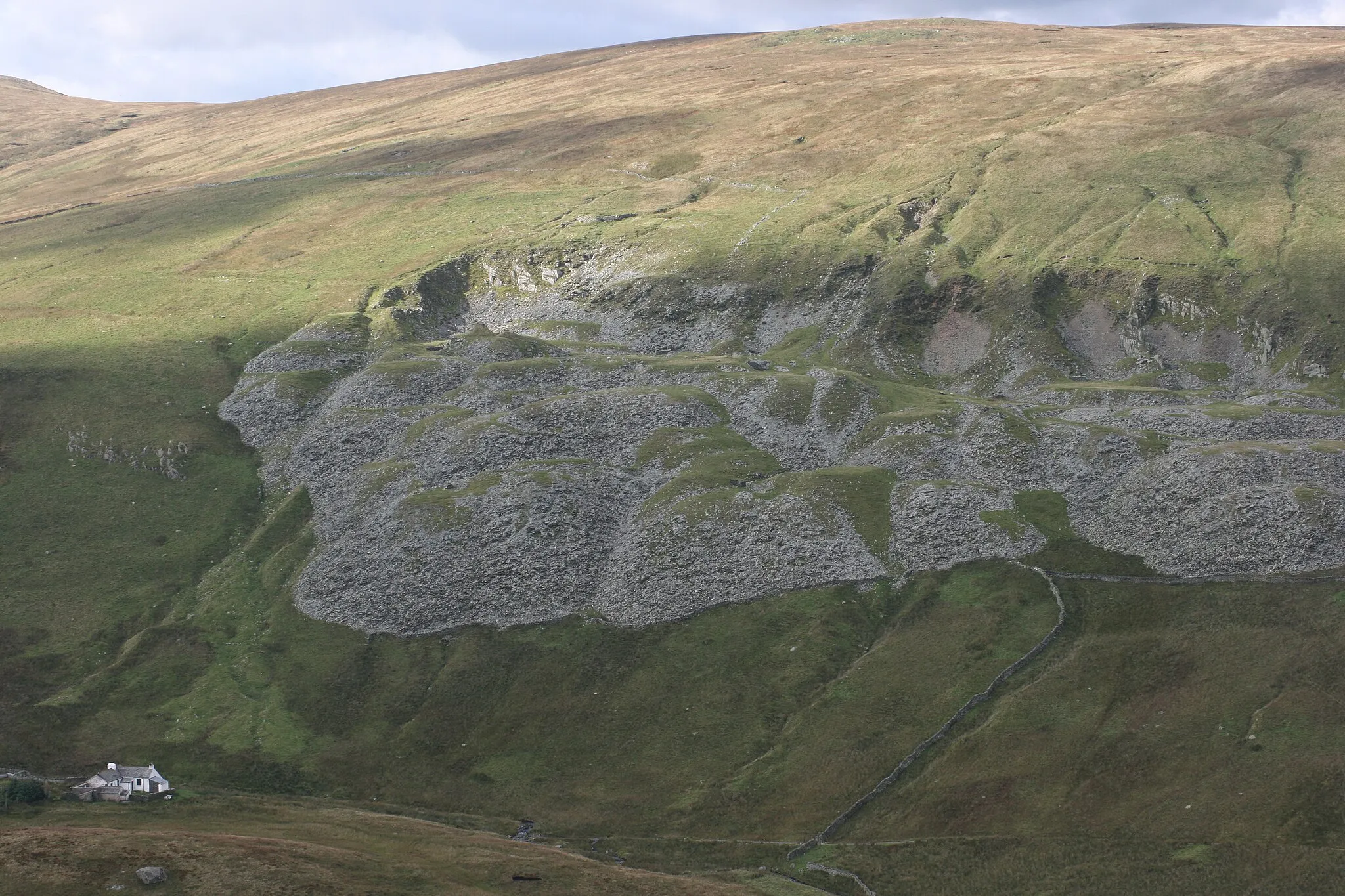 Photo showing: Mosedale cottage and quarry, Cumbria, England. If you look very closely you can see some tree guards at the top of the quarry around oaks planted by the RSPB Haweswater.