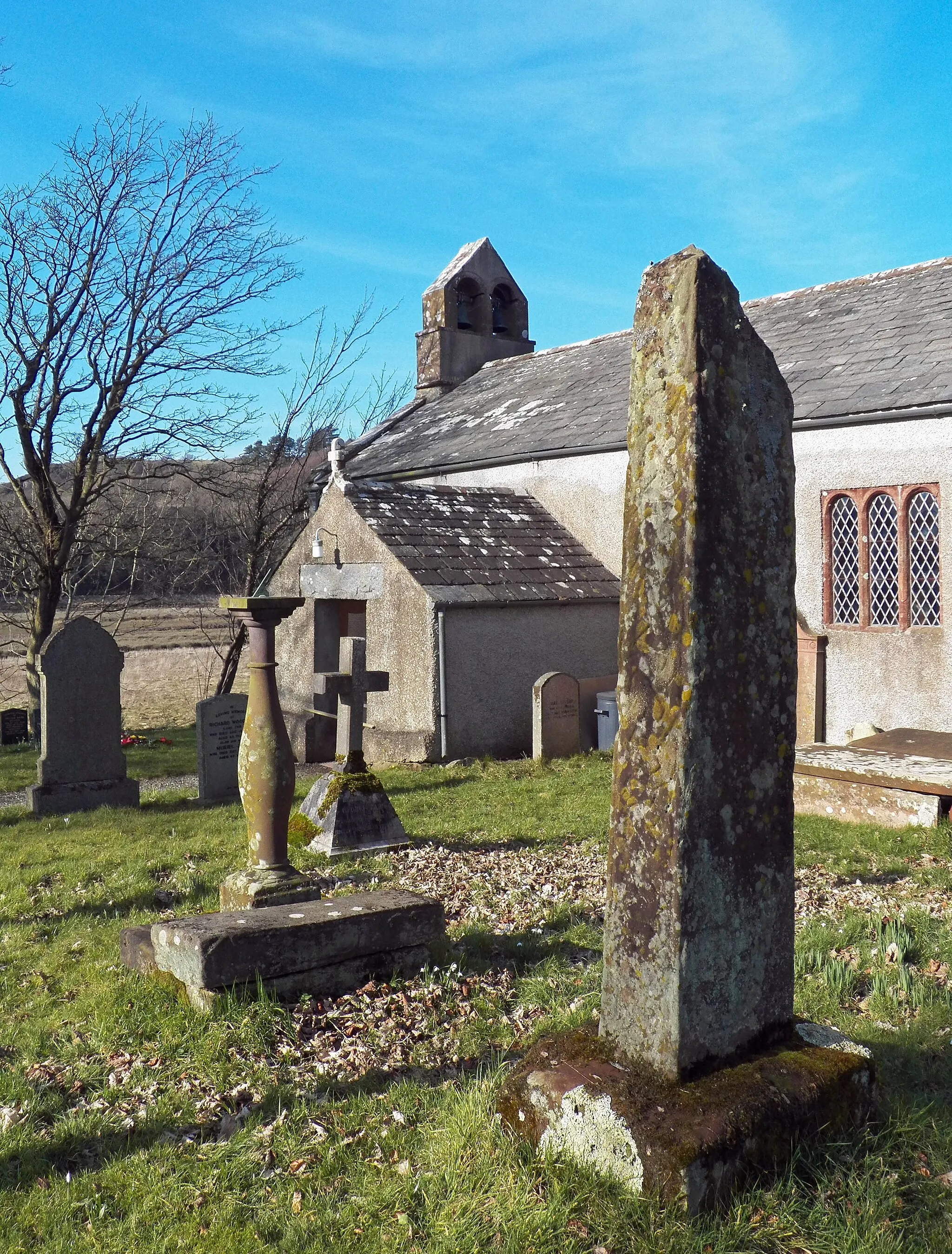 Photo showing: View of the two cross shafts at Waberthwaite, Cumbria. The large shaft is 10th century or earlier (Collingwood) and is Norse with Anglian characteristics. The second cross shaft is lying on the steps of the sundial.