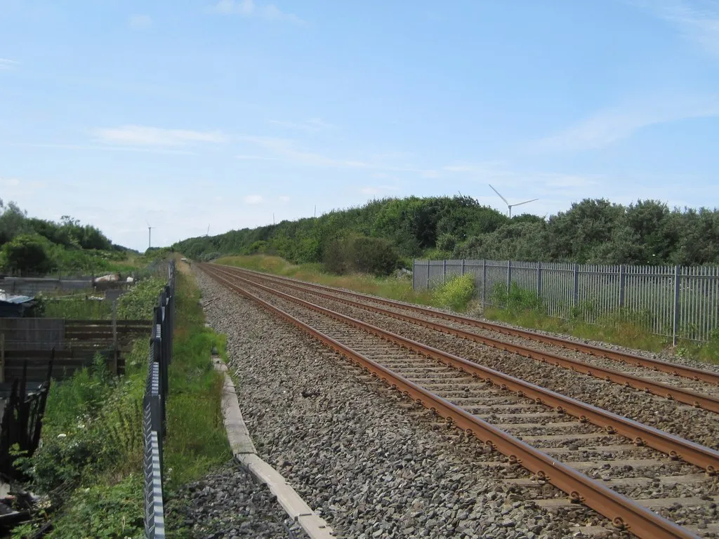 Photo showing: Siddick (Junction) railway station (site), Cumbria Opened in 1880 by the London & North Western Railway on the line from Barrow-in-Furness to Carlisle, this station closed in 1934. View south west towards Workington and Barrow.
Only old maps show this was the site, where the view of the track disappears. No trace remains, unless the small hump to the right of the track is the remains of a platform.