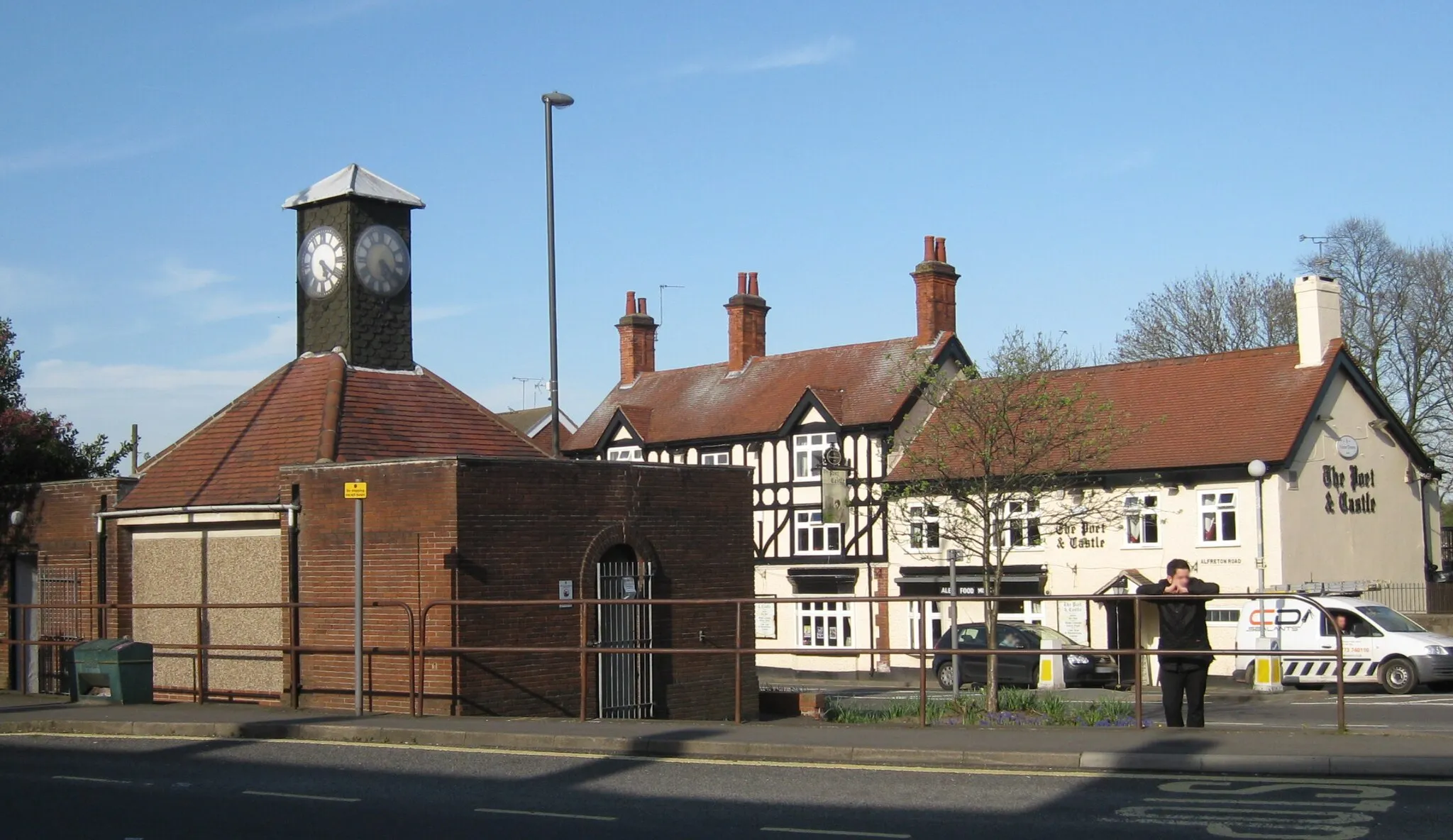 Photo showing: High Street, Codnor.  In the foreground is the Condor Clock, originally a 1930 bus shelter, to which a clock was added in 1950, now public toilets.  Behind it on Alfreton Road DE5 9QY is the Poet and Castle pub (formerly known as The Clock, originally 1862 the New Inn.).