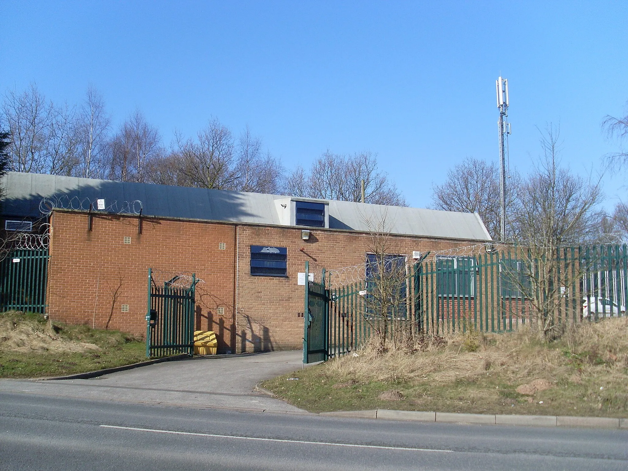 Photo showing: Telephone Exchange, New Ollerton This TE is situated on the B6387 Retford Road, Boughton, NG22 9JN adjacent to a disused railway line. Its appearance is not enhanced by the green fencing and razor sharp wiring above it. The mobile phone mast can be seen on the right of the photo.
