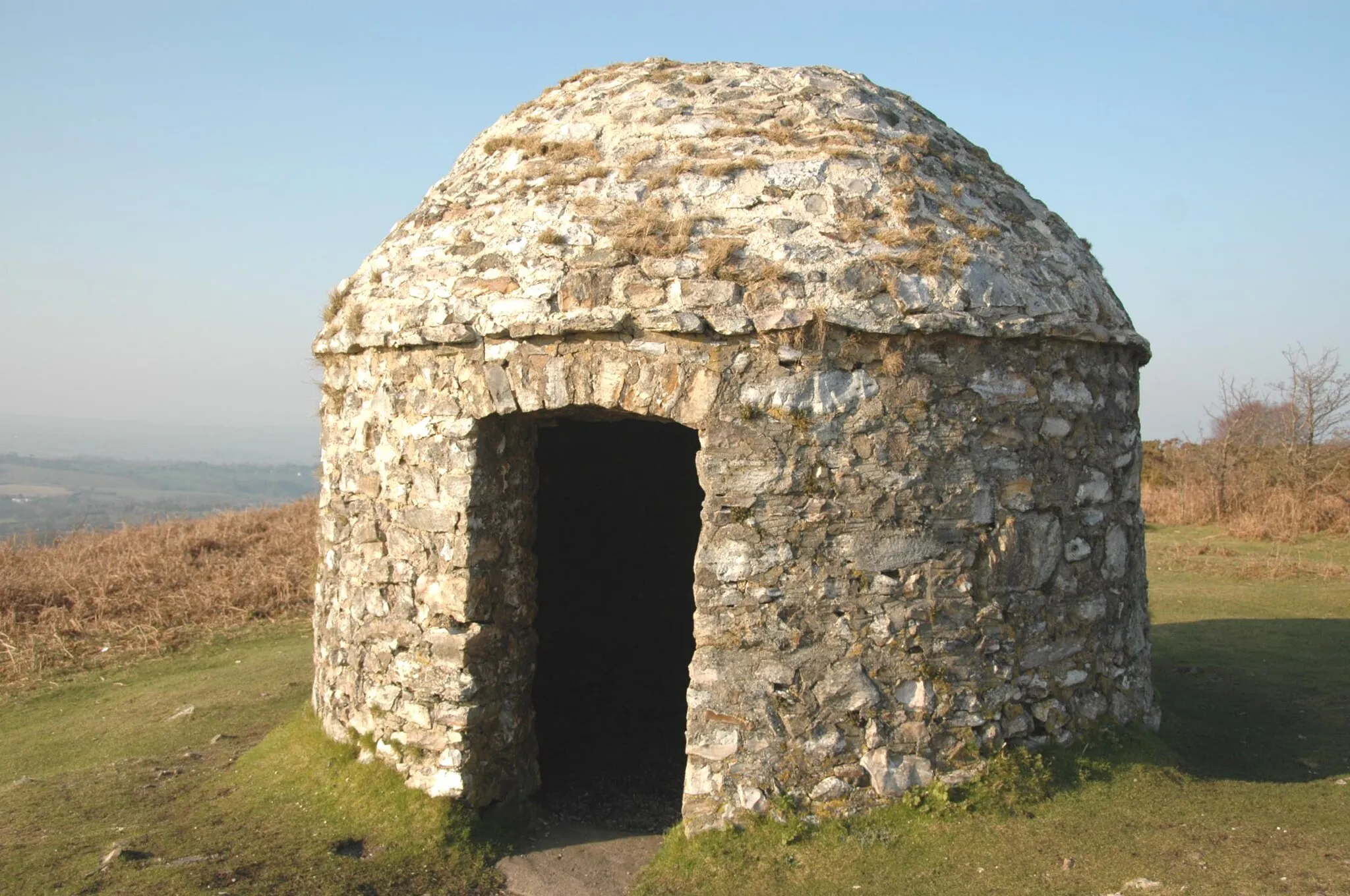 Photo showing: A stone building, a signal station, at Culmostock Beacon in Devon, UK, built in 1588 to enclose a wooden pole, which protruded through the roof to support one or more fire baskets. This is one of a chain of signal stations along England's southern counties - but the only remaining stone building - the purpose of which was to warn of the Spanish Armada being sighted. There is an adjacent Ordnance Survey (the UK's official mapping agency) trig point with the bench mark S.3745.