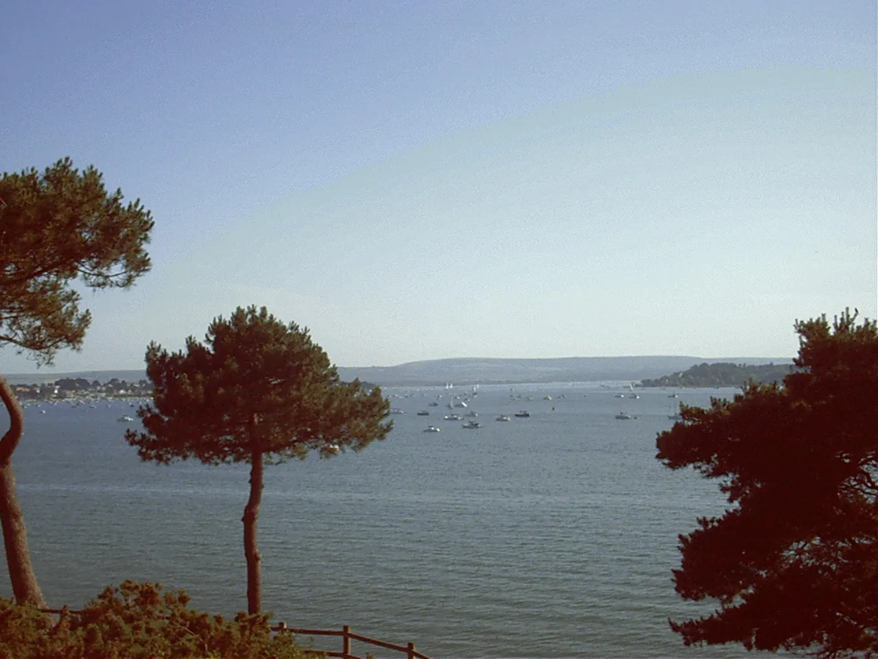 Photo showing: View across Poole Harbour, Purbecks in the distance (middle), sandbanks to the left and the end of Brownsea Island, taken June 2003