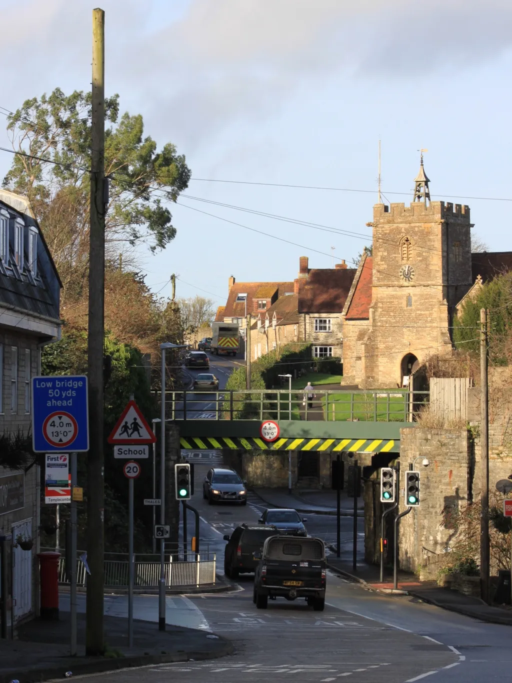 Photo showing: Looking north towards St Mary's church in Templecombe, Somerset. The bridge carries the Exeter to Salisbury railway line; the railway station is immediately to the left of this.