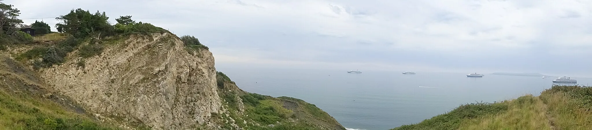 Photo showing: Panoramic view of Burning Cliff at Ringstead Bay and cruise ships during the COVID-19 pandemic in Weymouth Bay from the path to White Nothe, Dorset, England.