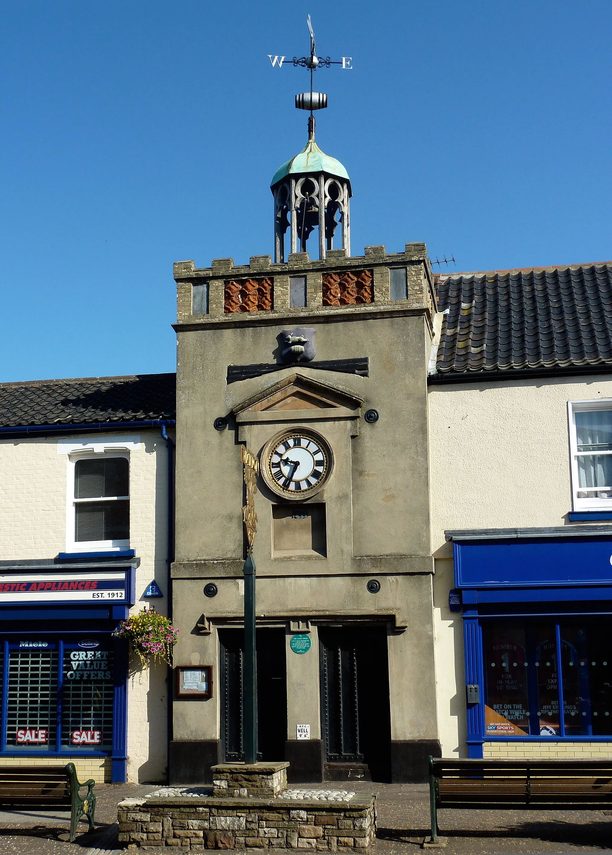 Photo showing: The old Clock Tower in Watton, Norfolk, England. The tower was built in 1679 to hold a fire warning bell following the 'Great Fire of Watton' that destroyed more than sixty properties in 1674. This early warning bell, known as 'Ting-Tang' sits in an ornate cupola on top of the tower.