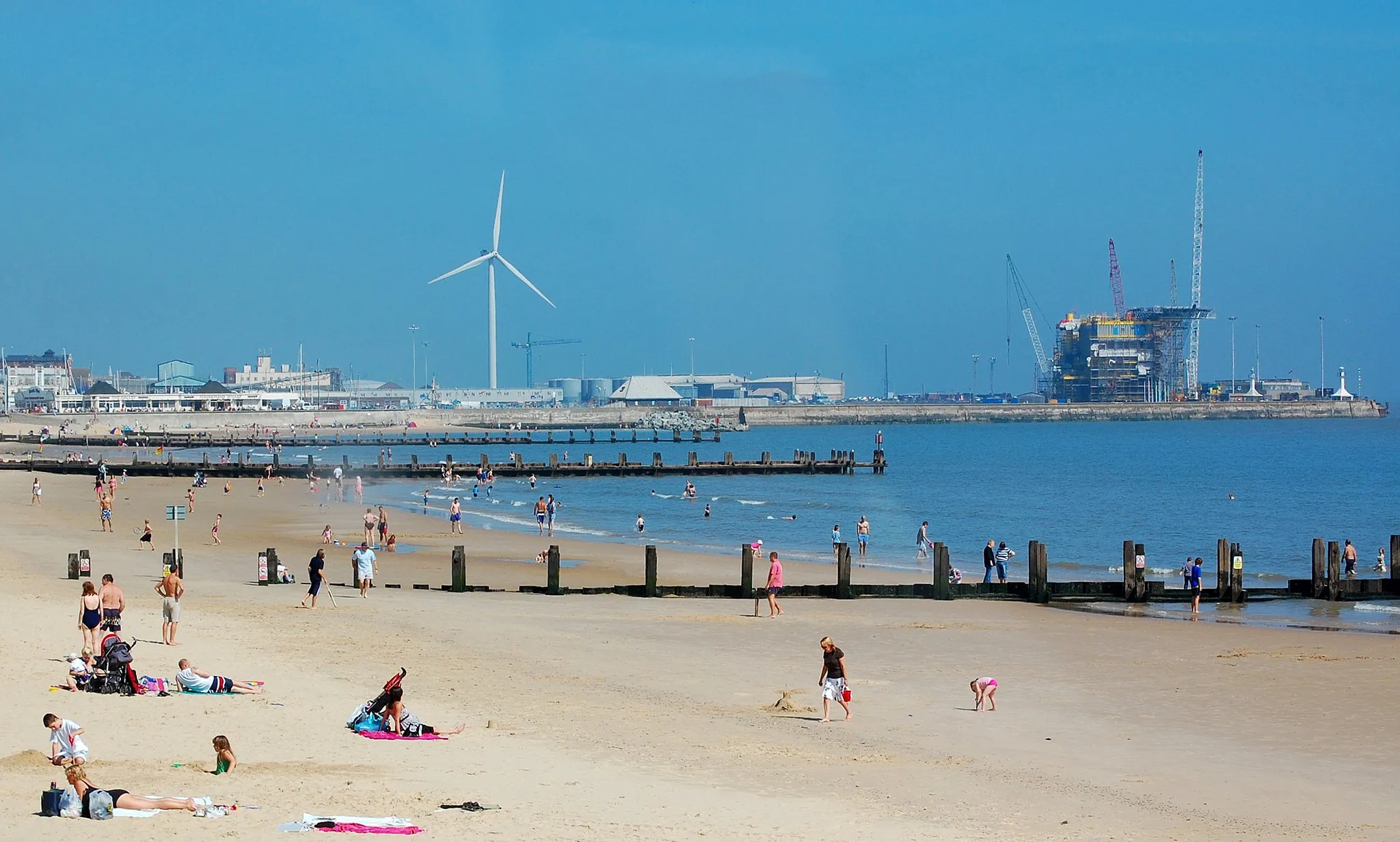 Photo showing: Lowestoft seafront showing the beach and the outer harbour with wind turbine and gas rig.