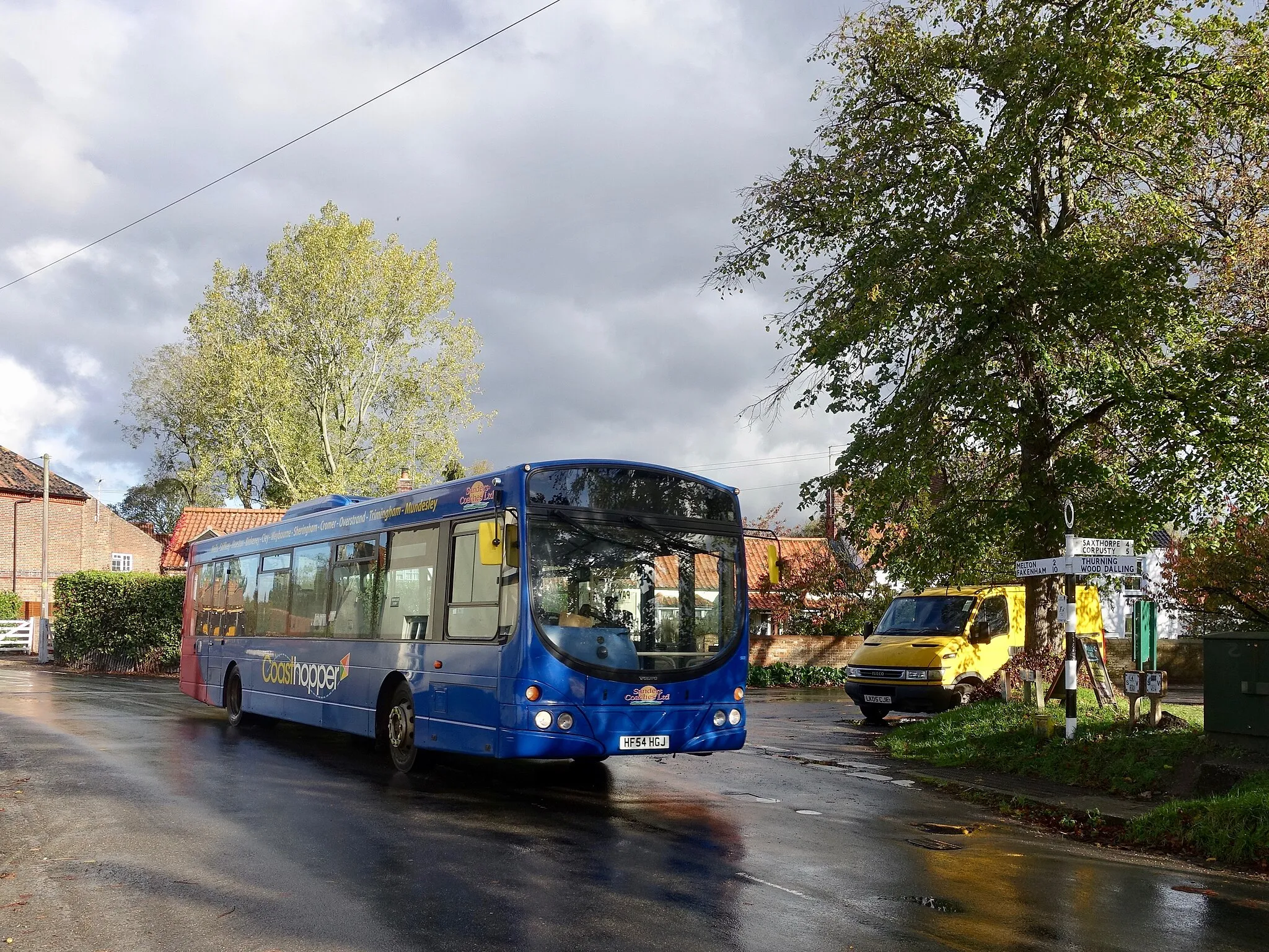 Photo showing: On schooldays, six different vehicles appear on service 9 over the course of the day; today, two Coasthopper branded buses (the other being 504) operated the most journeys. Here, Wright Eclipse Urban bodied Volvo B7RLE number 507 is in Briston
Behind the fingerpost is a sign advertising Norfolk-C-Larder, a surprising backstreet fishmonger on Mill Road. The bench that used to be out of shot to the right has recently disappeared